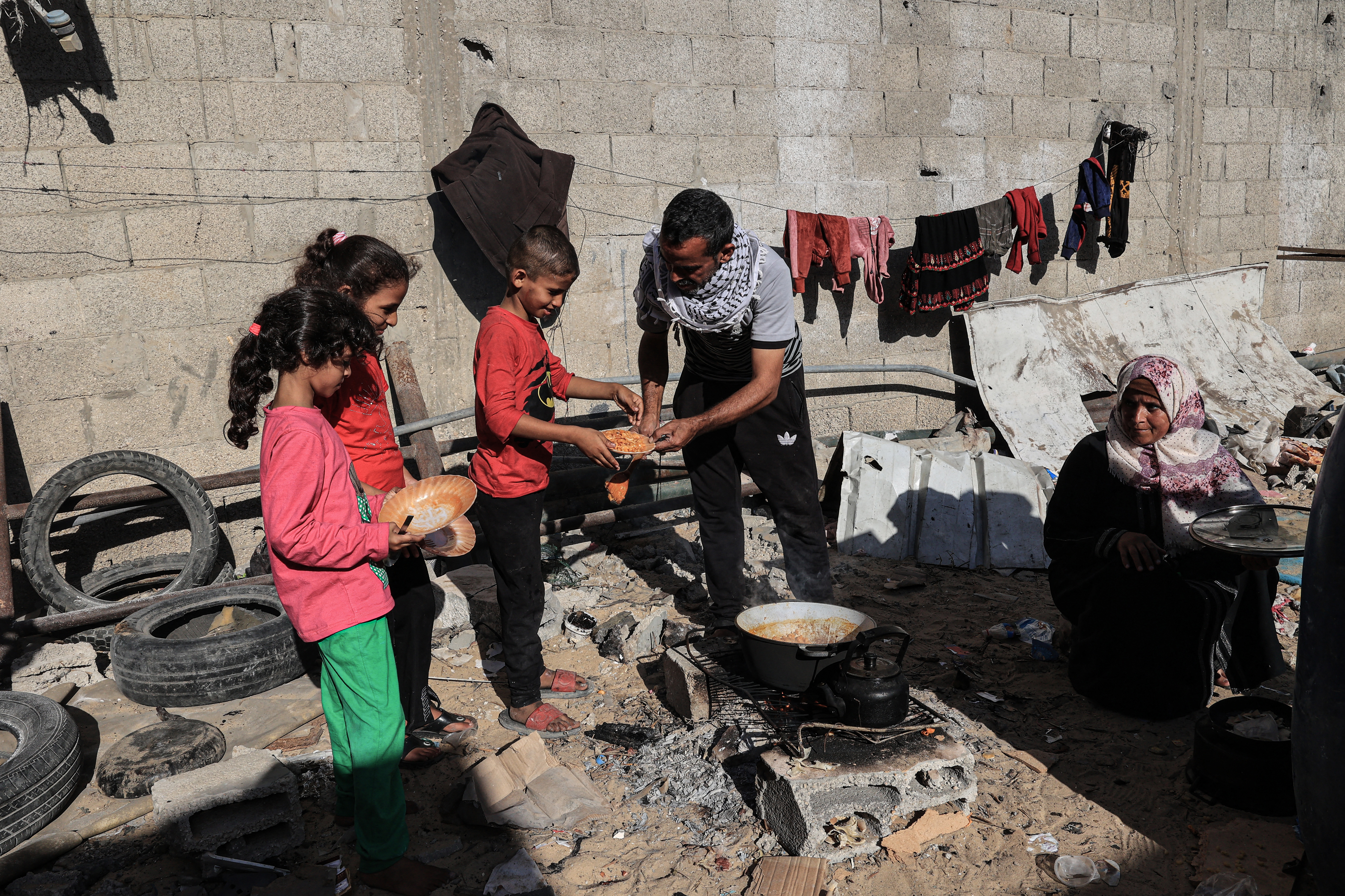 Amal al-Robayaa (R) looks on as her husband Imed serves the children their meals