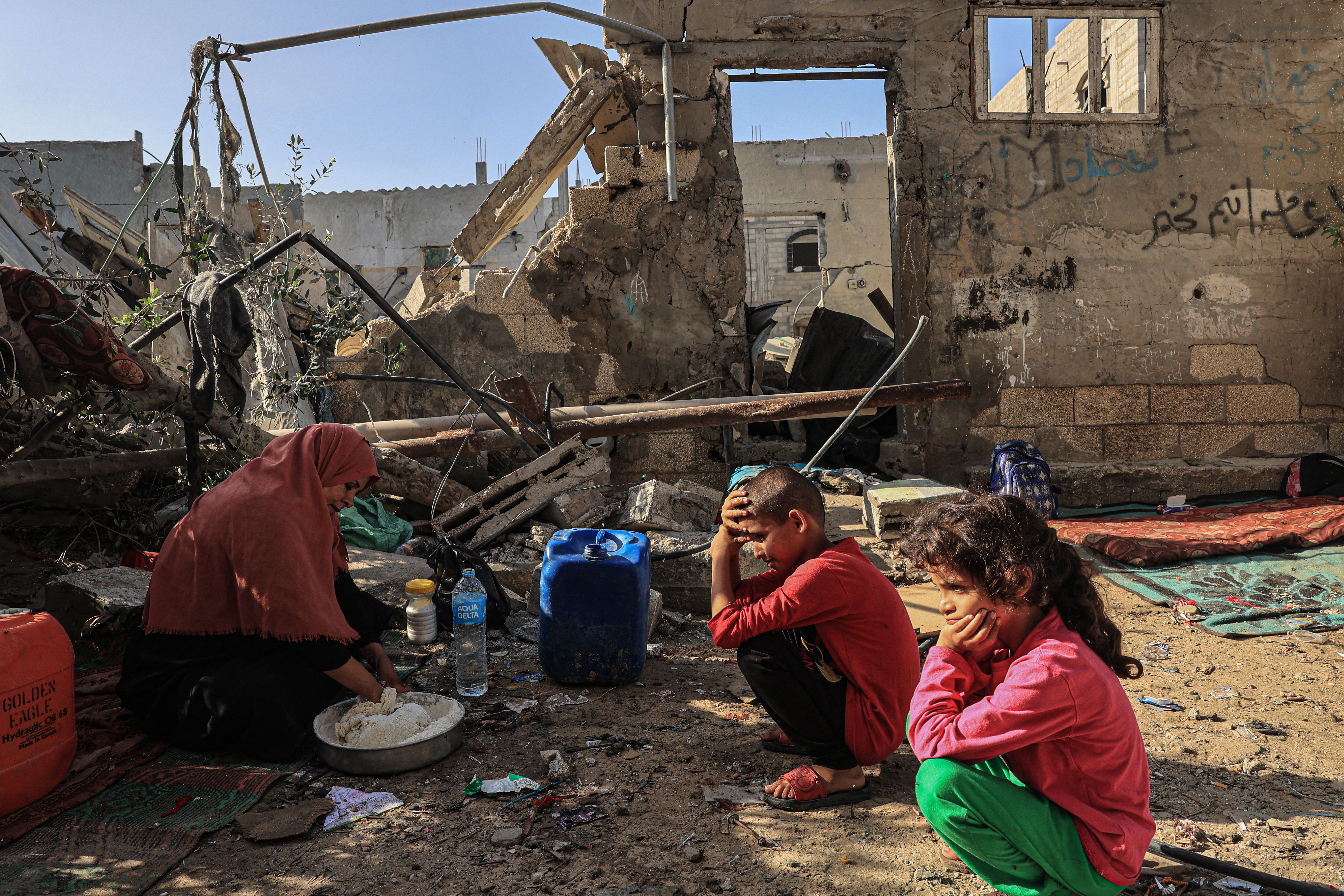 Nesrine, Amal al-Robayaa's sister-in-law, mixes flour with water to make bread as her grandchildren watch