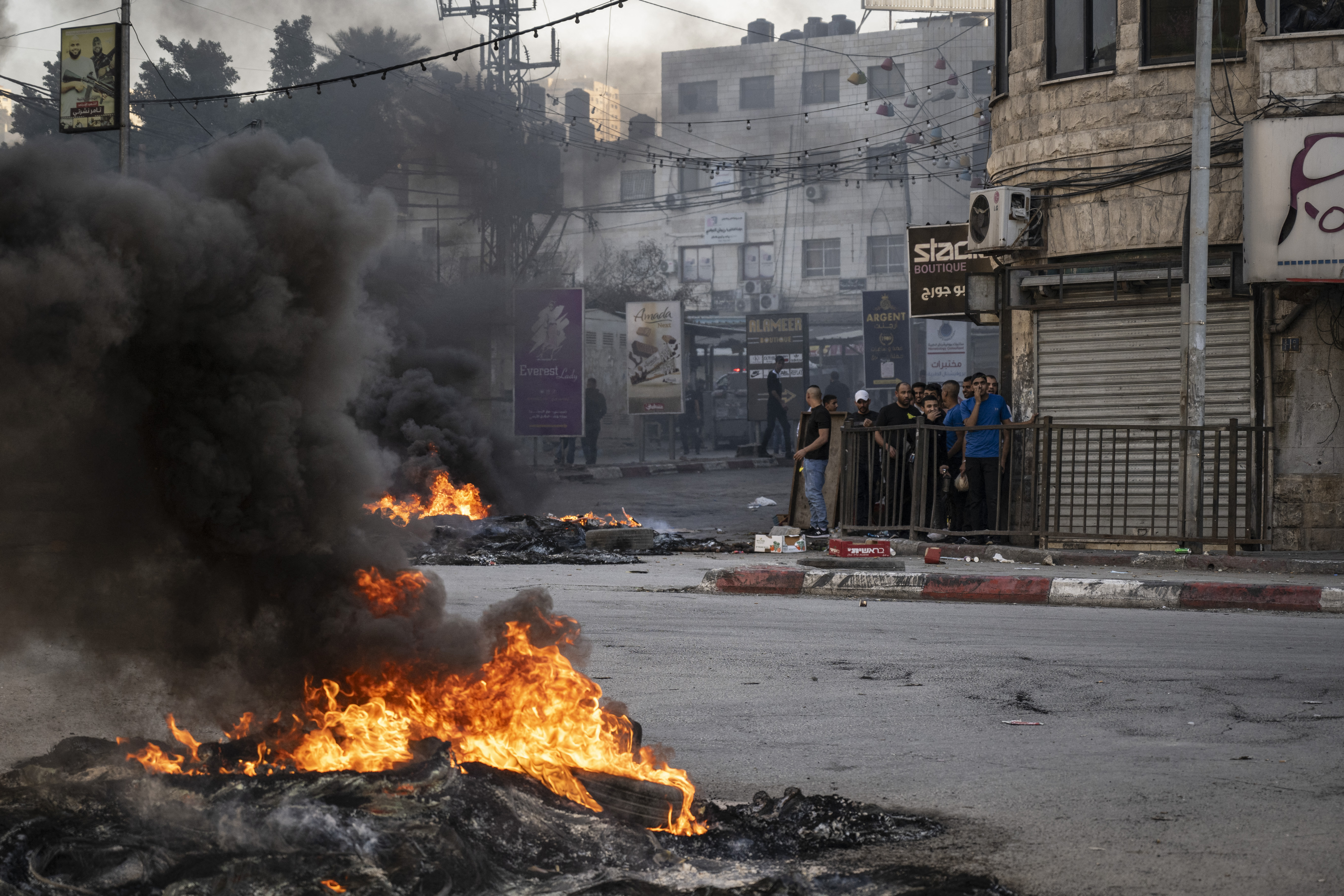 Palestinian youths take cover behind a wall during confrontations with Israeli forces in the occupied West Bank city of Jenin.