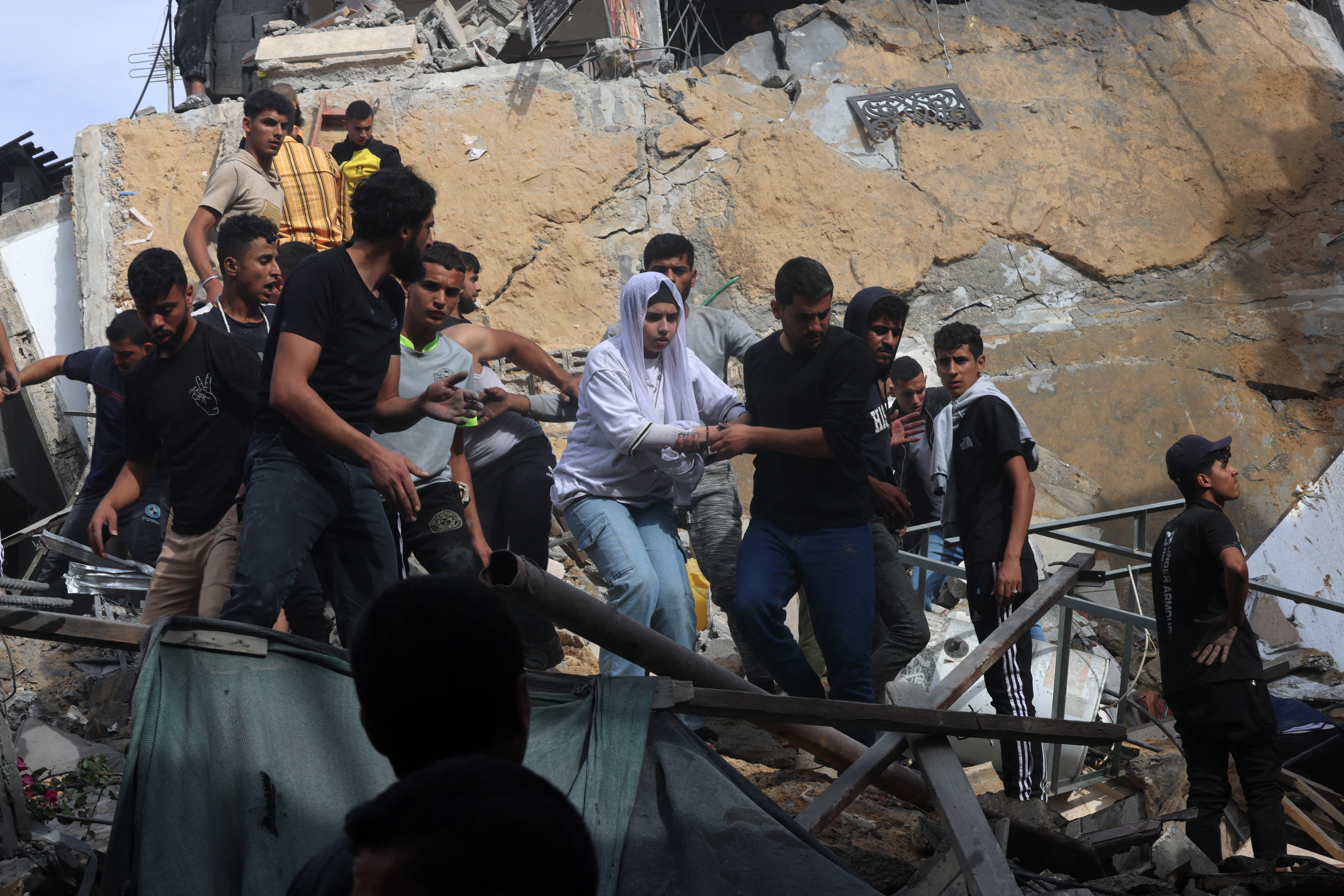 A woman is helped down from a building destroyed during Israeli bombing on Rafah