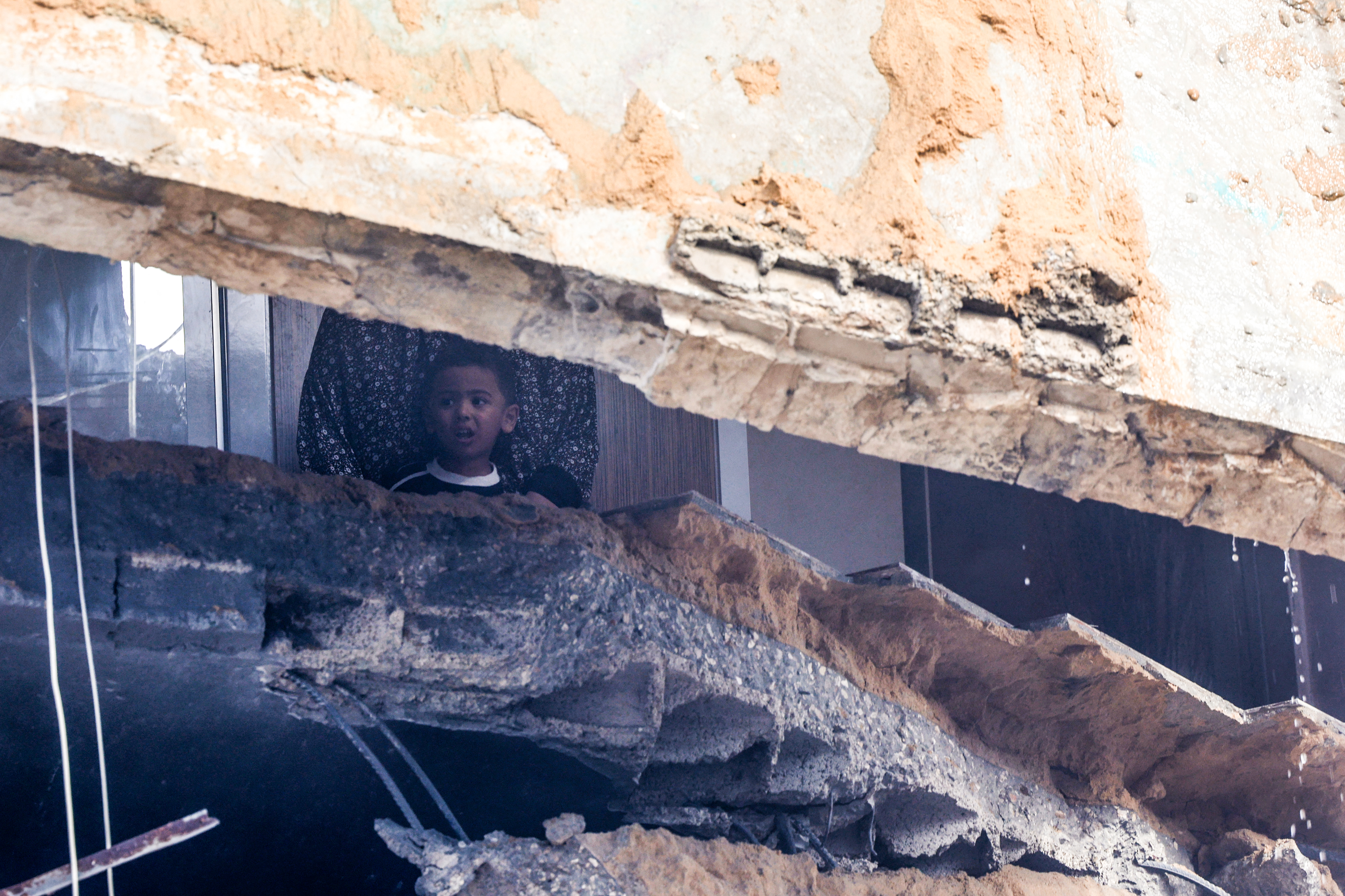 A child and woman wait for help as they remain trapped inside a building destroyed during Israeli bombing, in Rafah in the southern Gaza Strip