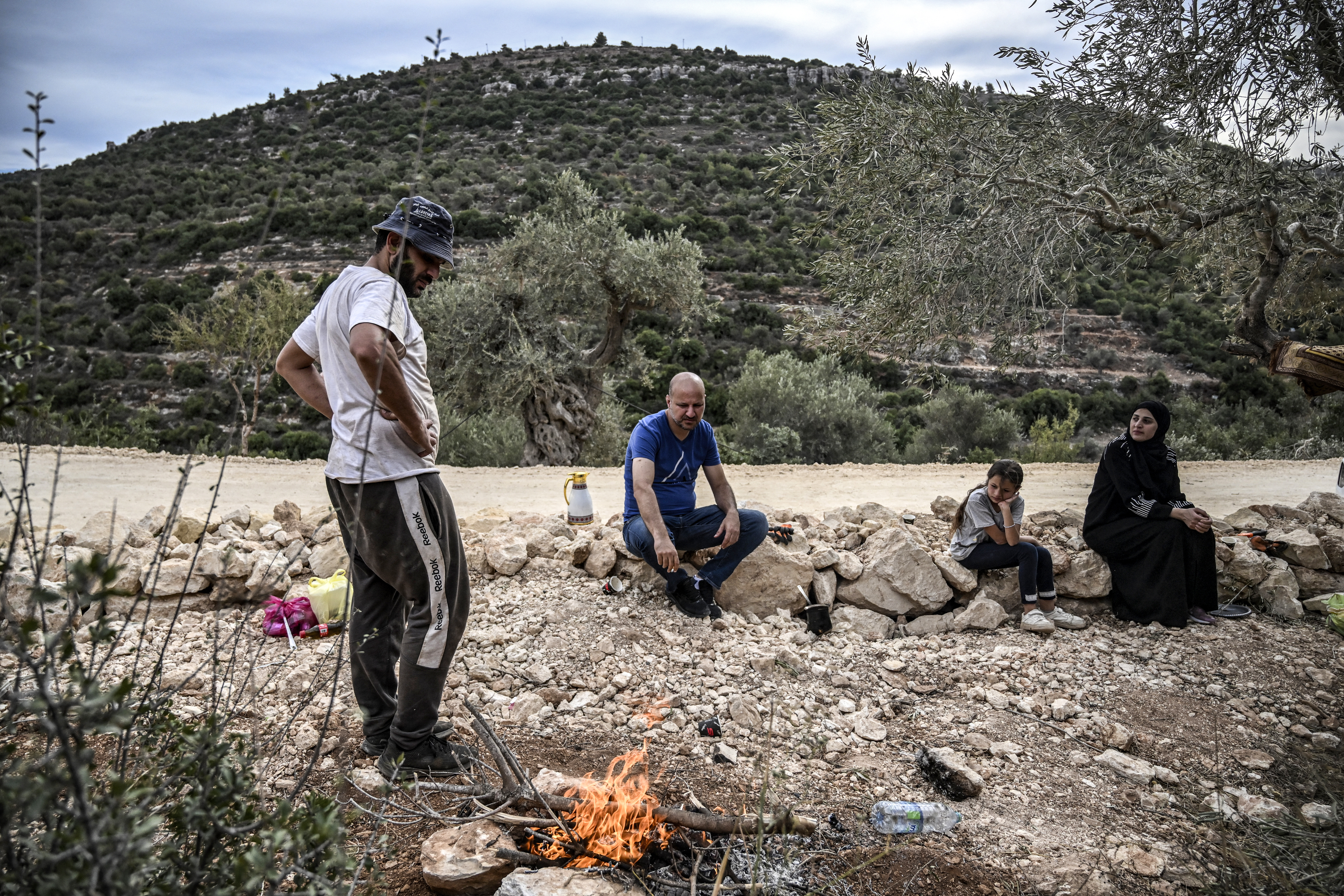 A Palestinian man stands by a fire before cooking for his family during the olive harvest at a grove outside Ramallah in the occupied West Bank.