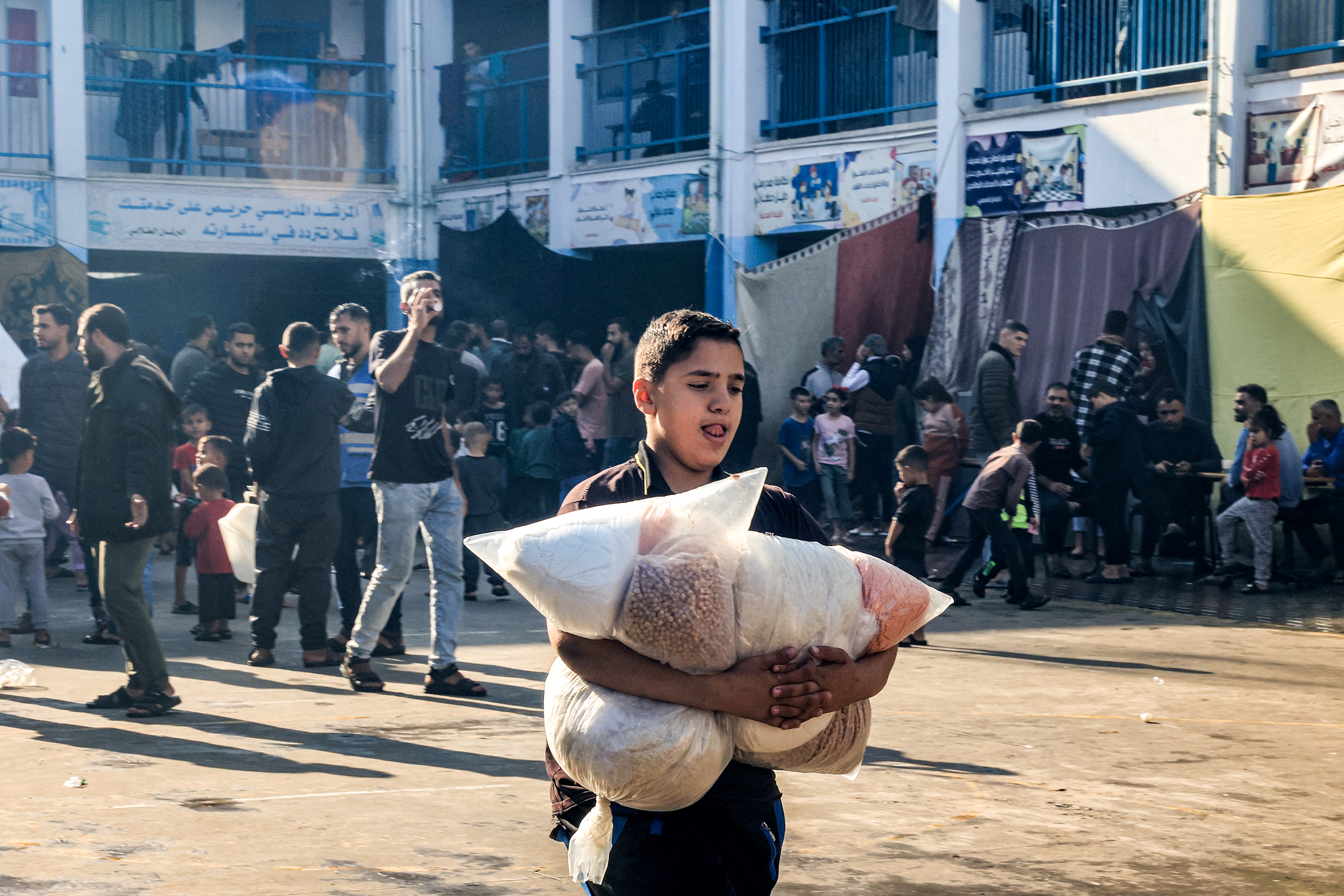 A boy walks with sacks of food supplies through a yard at a school run by the United Nations Relief and Works Agency for Palestine Refugees (UNRWA) in Rafah in the southern Gaza Strip 