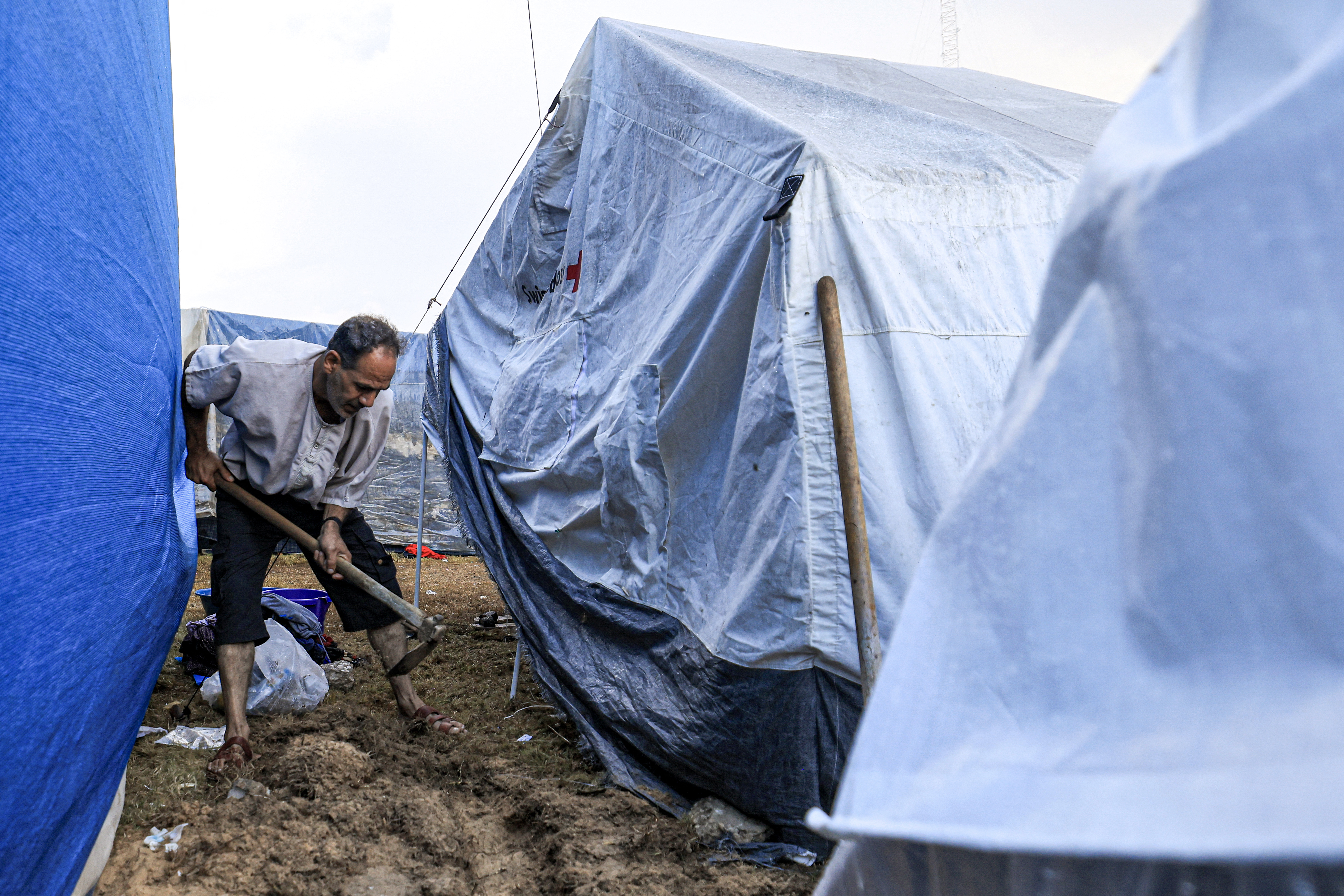 A man digs with a shovel outside a tent among others pitched by Palestinians taking shelter from Israeli bombardment around Nasser Hospital, in Khan Yunis in the southern Gaza Strip on November 14