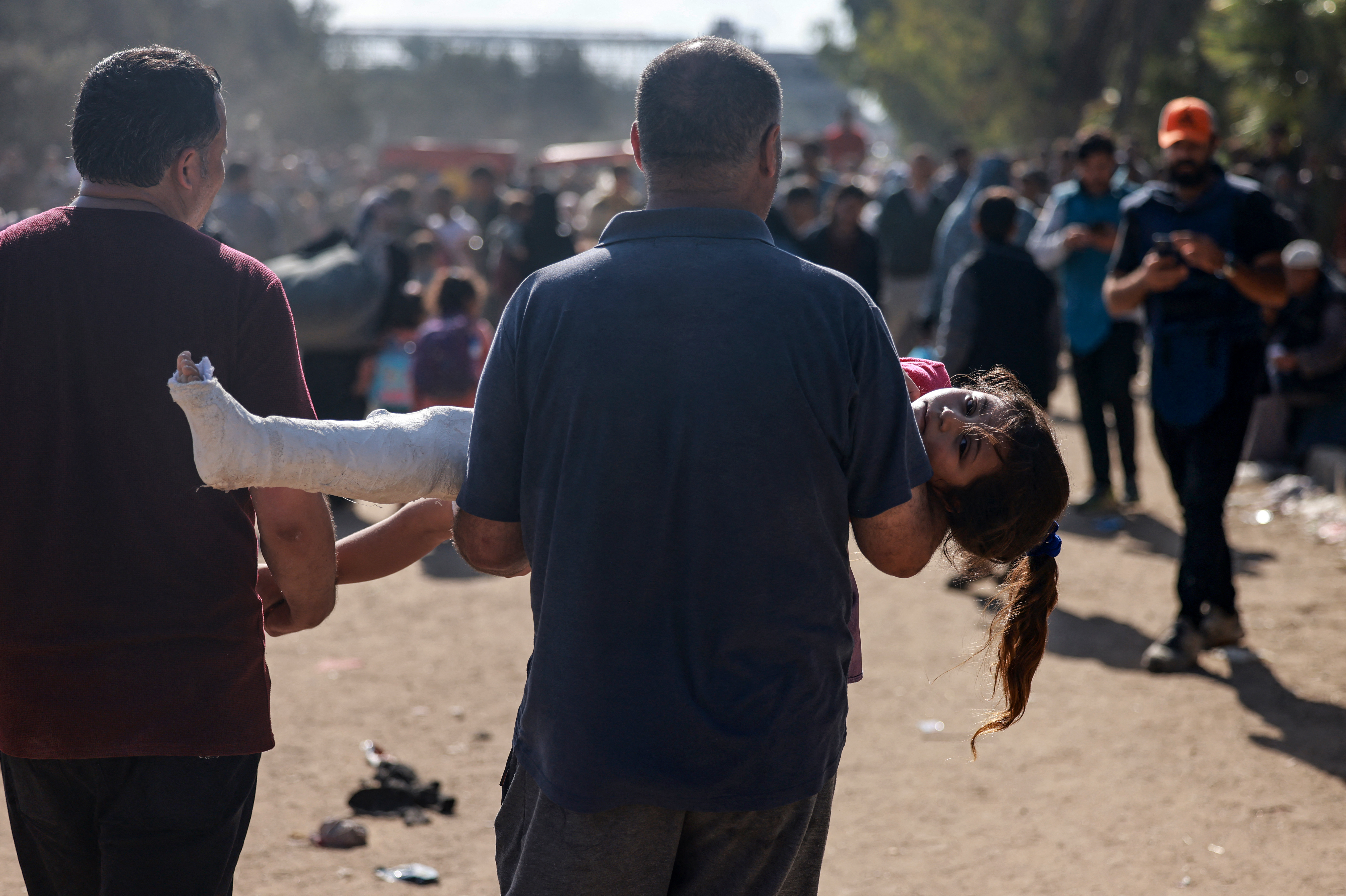 A man carries an injured child as Palestinians fleeing Gaza City and other parts of northern Gaza, walk along a road leading to the southern areas of the enclave.