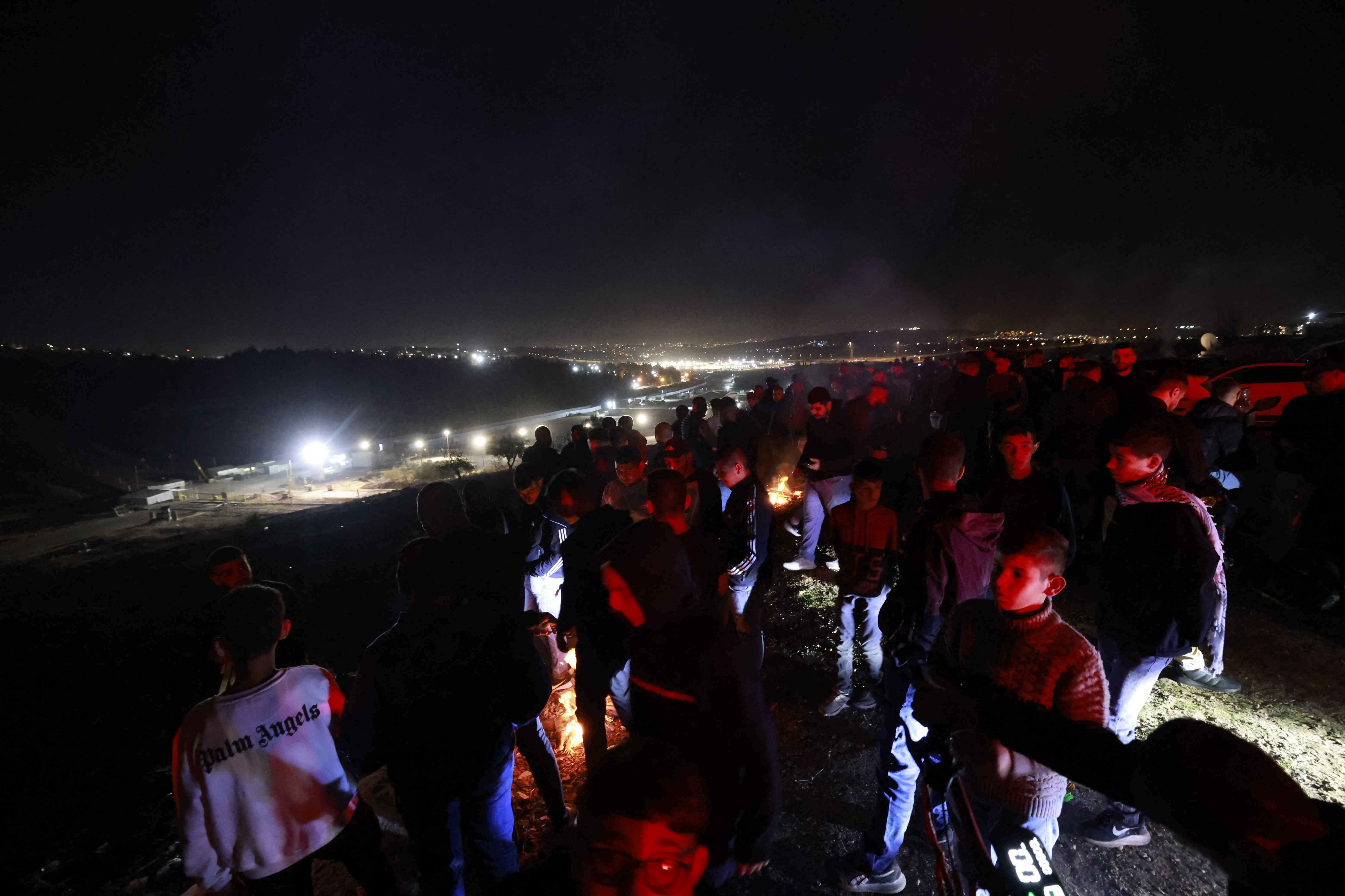 People gather on a hill overlooking the Israeli Ofer military facility in Baytunia in the occupied West Bank as they wait for the release of Palestinian prisoners in exchange for Israeli hostages freed by Hamas in Gaza on November 24