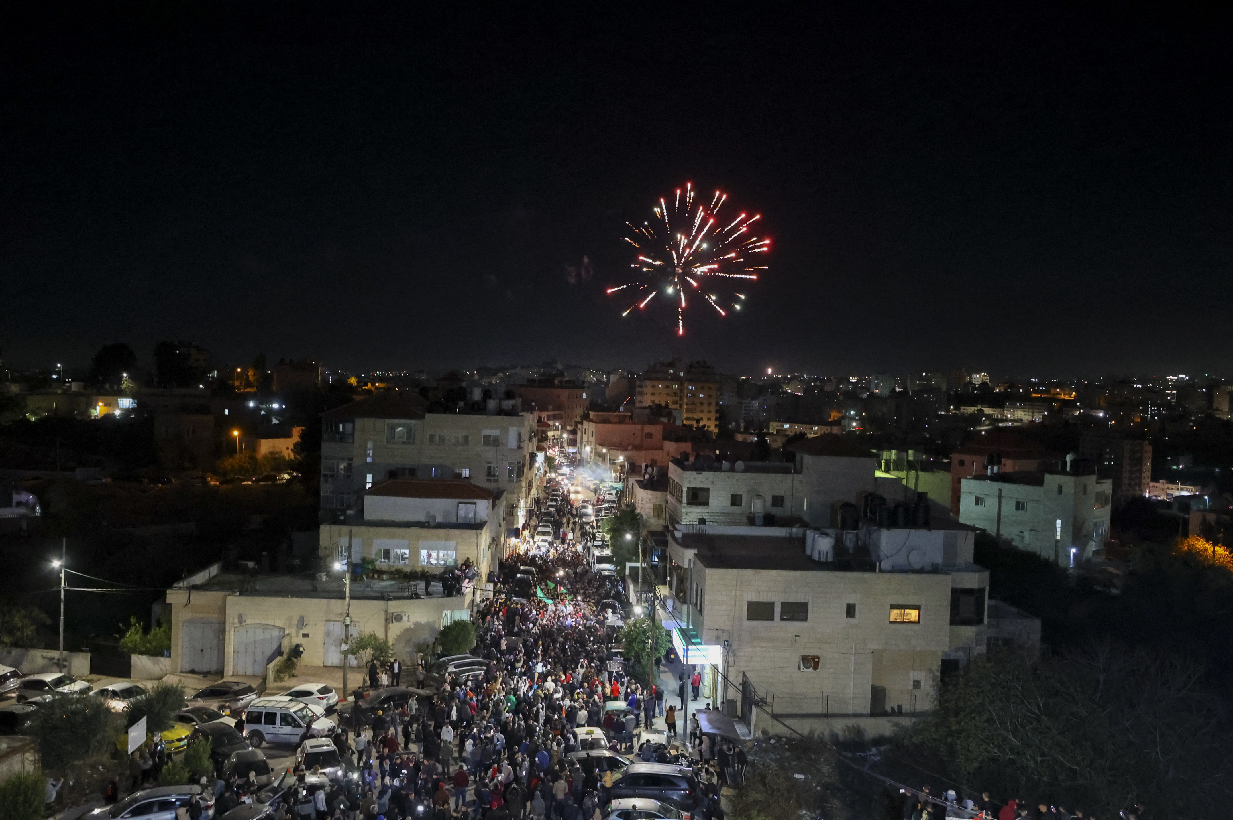 Fireworks streak accross the sky as Palestinian prisoners that were released from the Israeli Ofer military facility in exchange for hostages freed by Hamas in Gaza, are paraded in Baytunia in the occupied West Bank on November 24, 2023. - After 48 days of gunfire and bombardment that claimed thousands of lives, the first hostages to be released under a truce deal between Israel and Hamas were handed over on November 24, both sides said, nearly seven weeks after they were seized