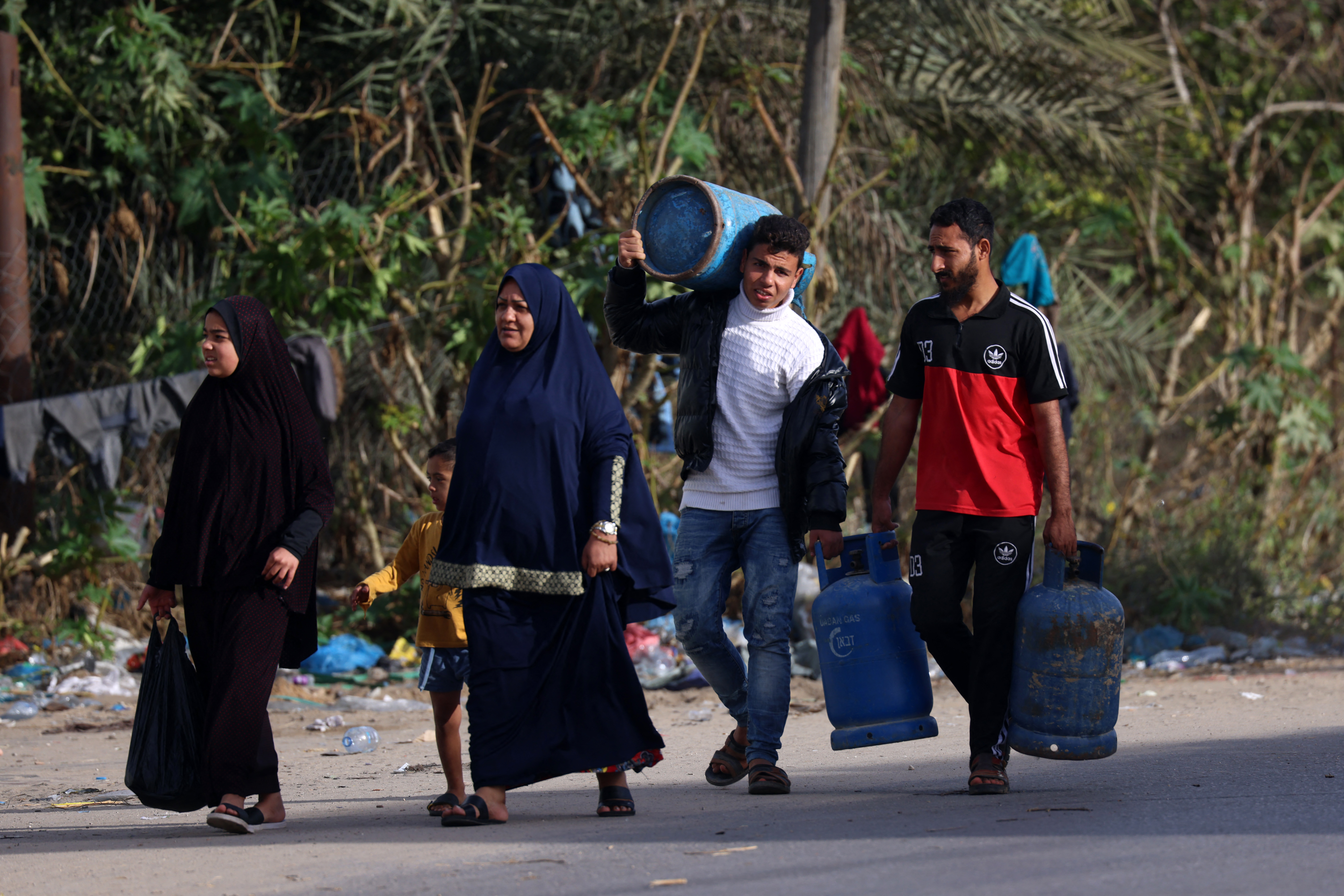 Children use a donkey-pulled cart to transport empty gas canisters to be filled with cooking gas from a tank that entered the Palestinian enclave via the Rafah crossing with Egypt, in Rafah in the southern Gaza Strip on November 25