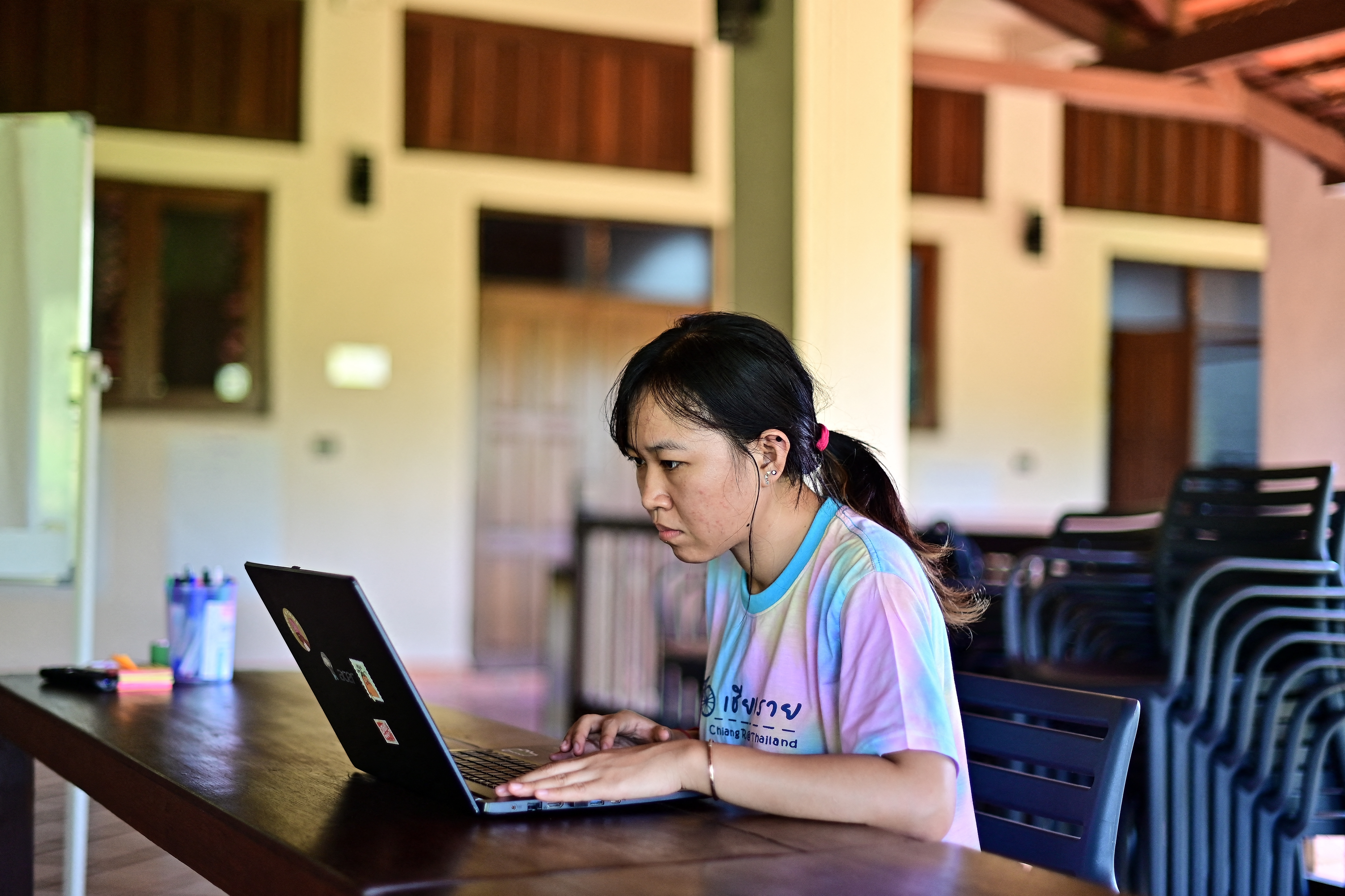 This photograph taken on November 21, 2023 shows San Somanear, an environmentalist from Cambodia, working on her laptop at the EarthRights School in Chiang Mai.