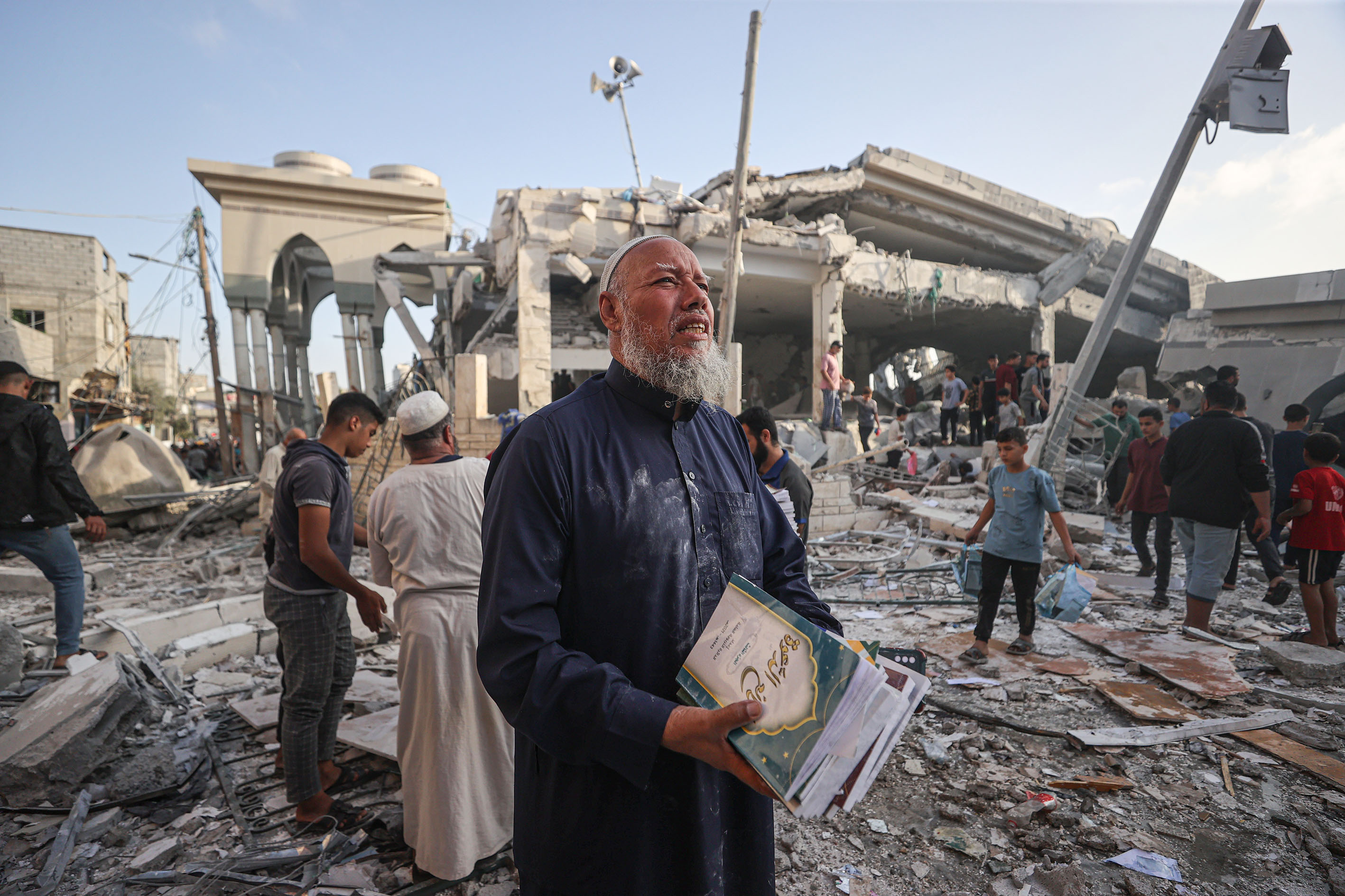 :Palestinians collect the Qorans near destroyed Khalid ibn al-Walid Mosque after Israeli airstrikes in Khan Yunis