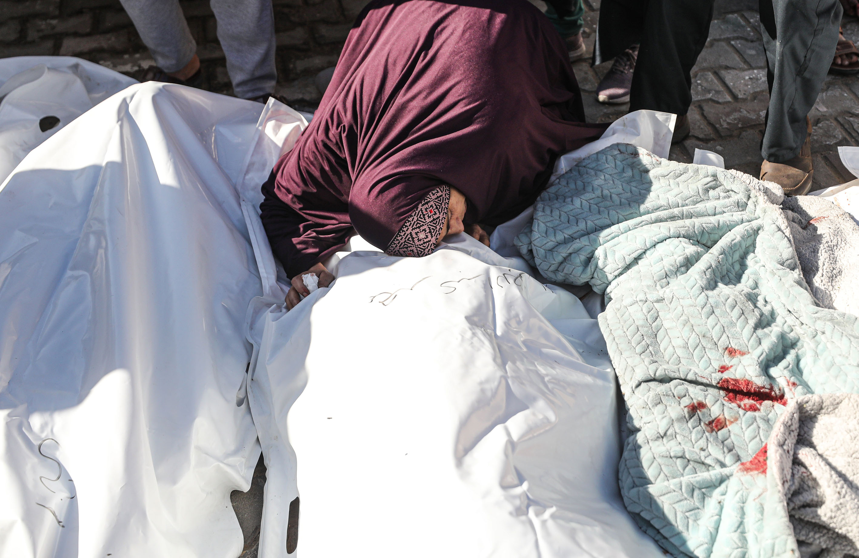 A relative of Palestinians who lost their lives in Israeli attacks, mourns near the bodies are taken from morgue of Al-Aqsa Martyr's Hospital to bury on the 46th day of Israeli attacks in Deir al-Balah, Gaza.