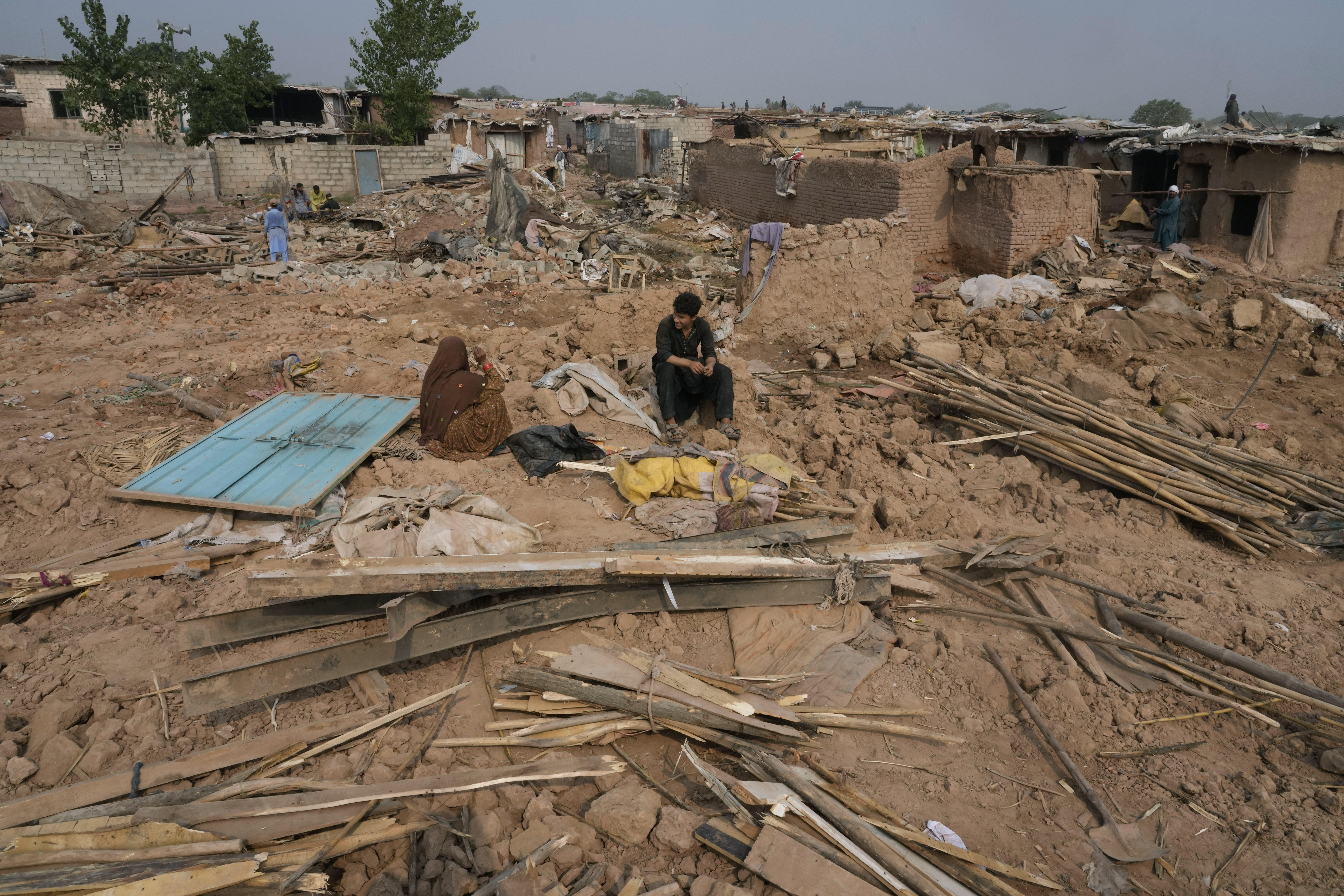 An Afghan family rests over the rubble as others retrieve useful stuff from their damage mud homes demolished by authorities during a crackdown against an illegal settlement and immigrants, on the outskirts of Islamabad, Pakistan.