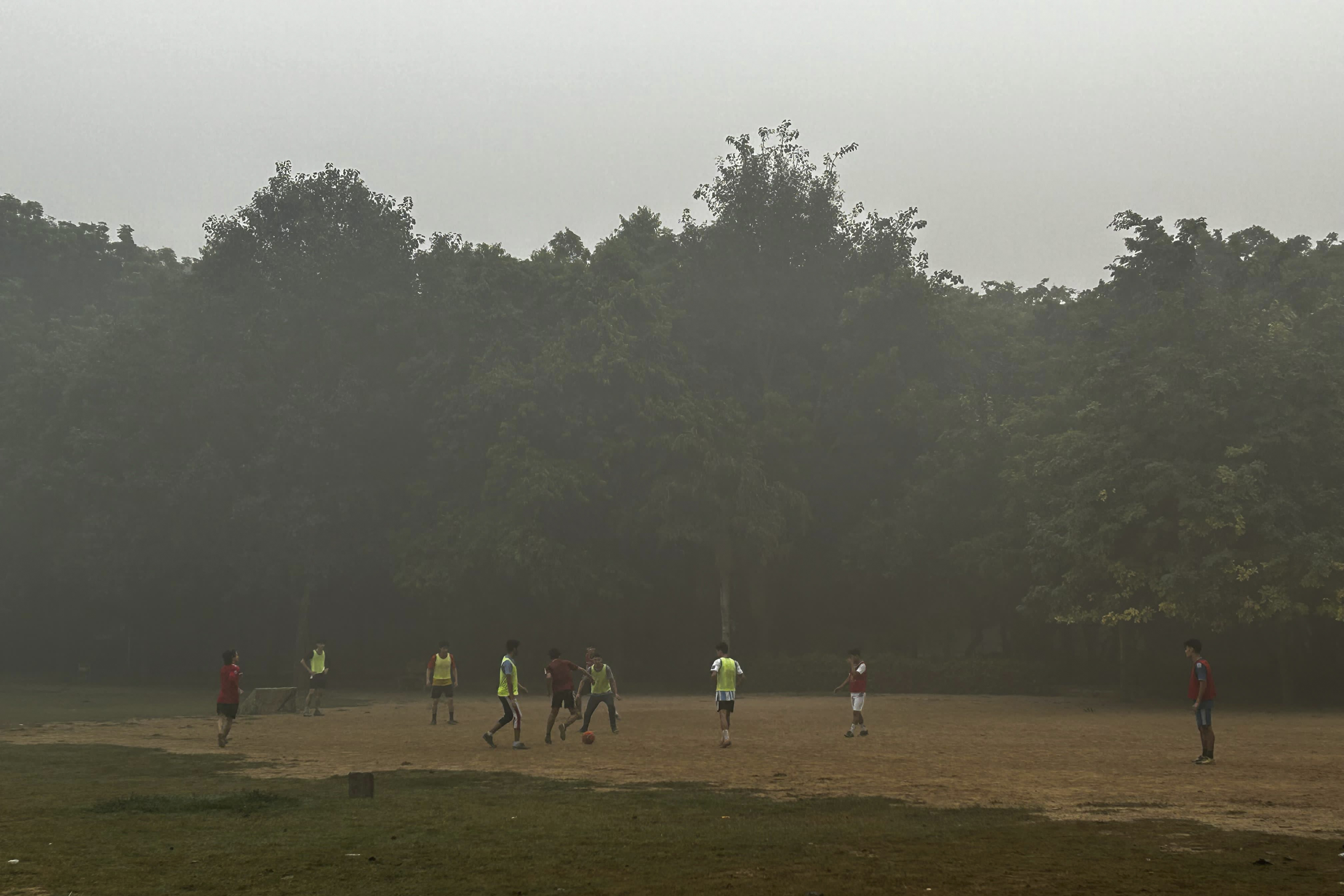 Children play soccer early morning in a park enveloped by smog and fog in New Delhi