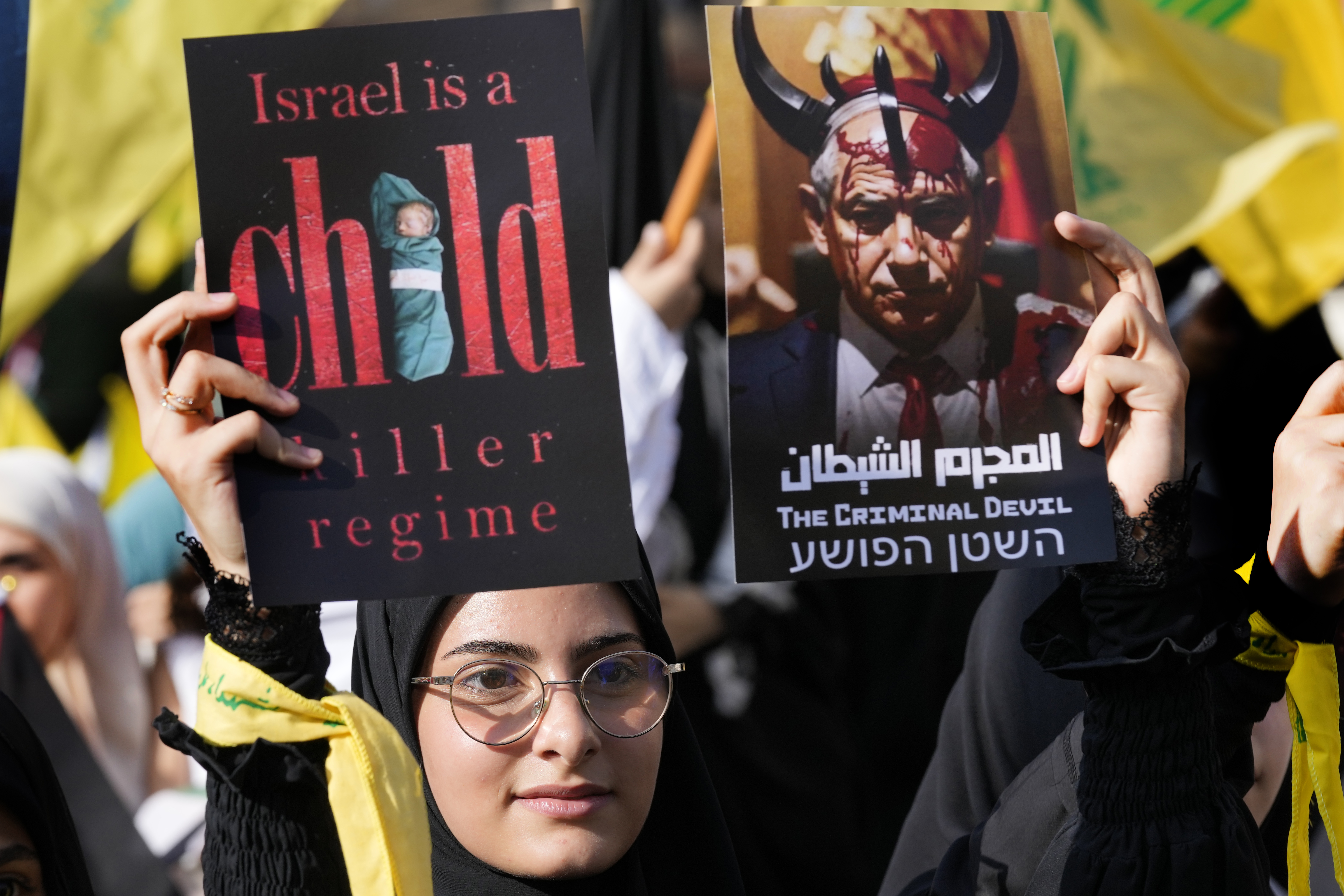 A supporter of the Iranian-backed Hezbollah group hold posters against the Israeli Prime Minister Benjamin Netanyahu, as she waits the speech of Hezbollah leader Sayyed Hassan Nasrallah during a rally to commemorate Hezbollah fighters who were killed in South Lebanon last few weeks while fighting against the Israeli forces, in Beirut, Lebanon.