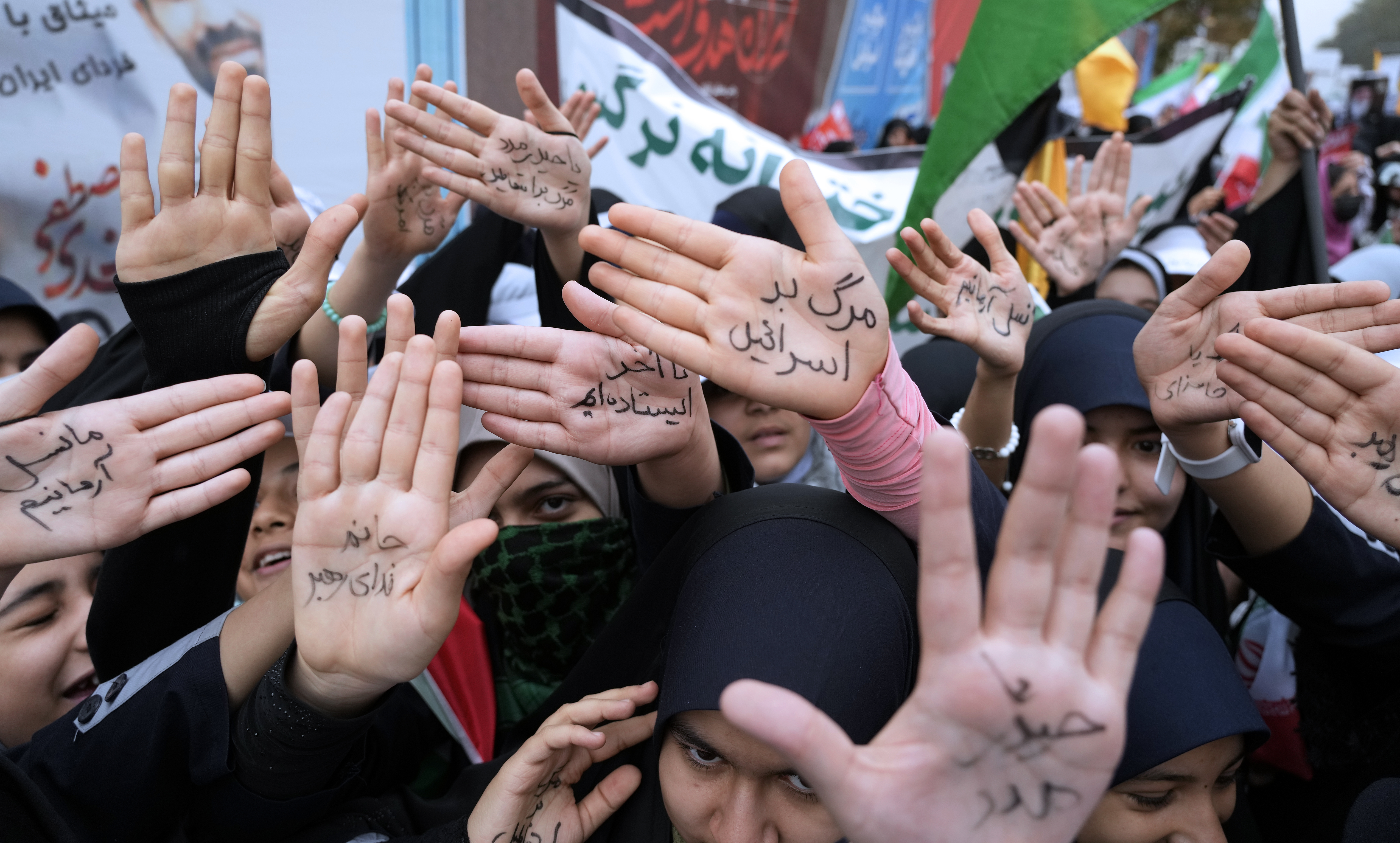 Iranian school girls show their hands with pro-government slogans and an anti-Israeli slogan which reads in Farsi: "Death to Israel", during a rally in front of the former U.S. Embassy in Tehran, Iran.