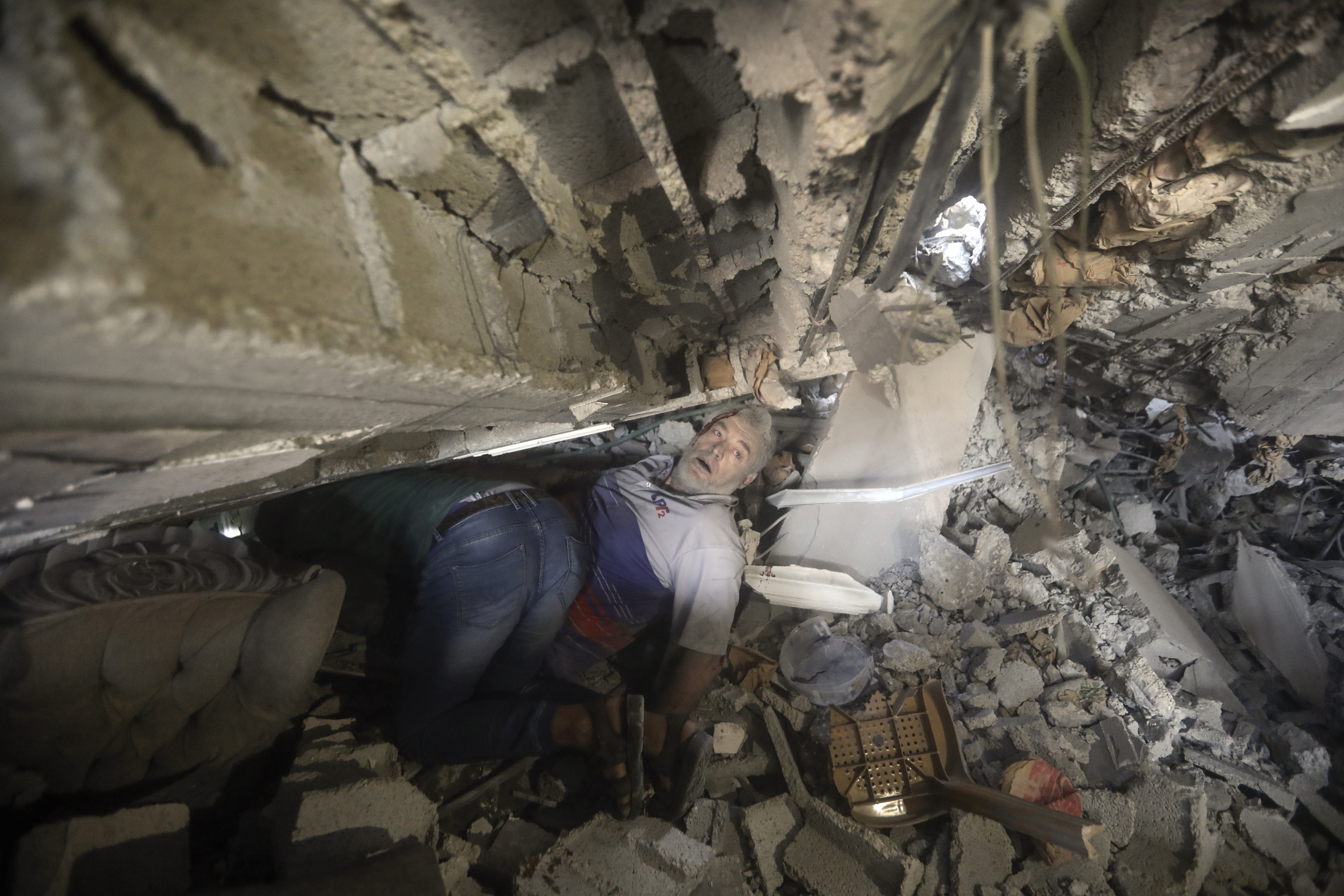 Palestinians try to release a man from under the rubble of a destroyed building following an Israeli airstrike in Khan Younis refugee camp, southern Gaza Strip.