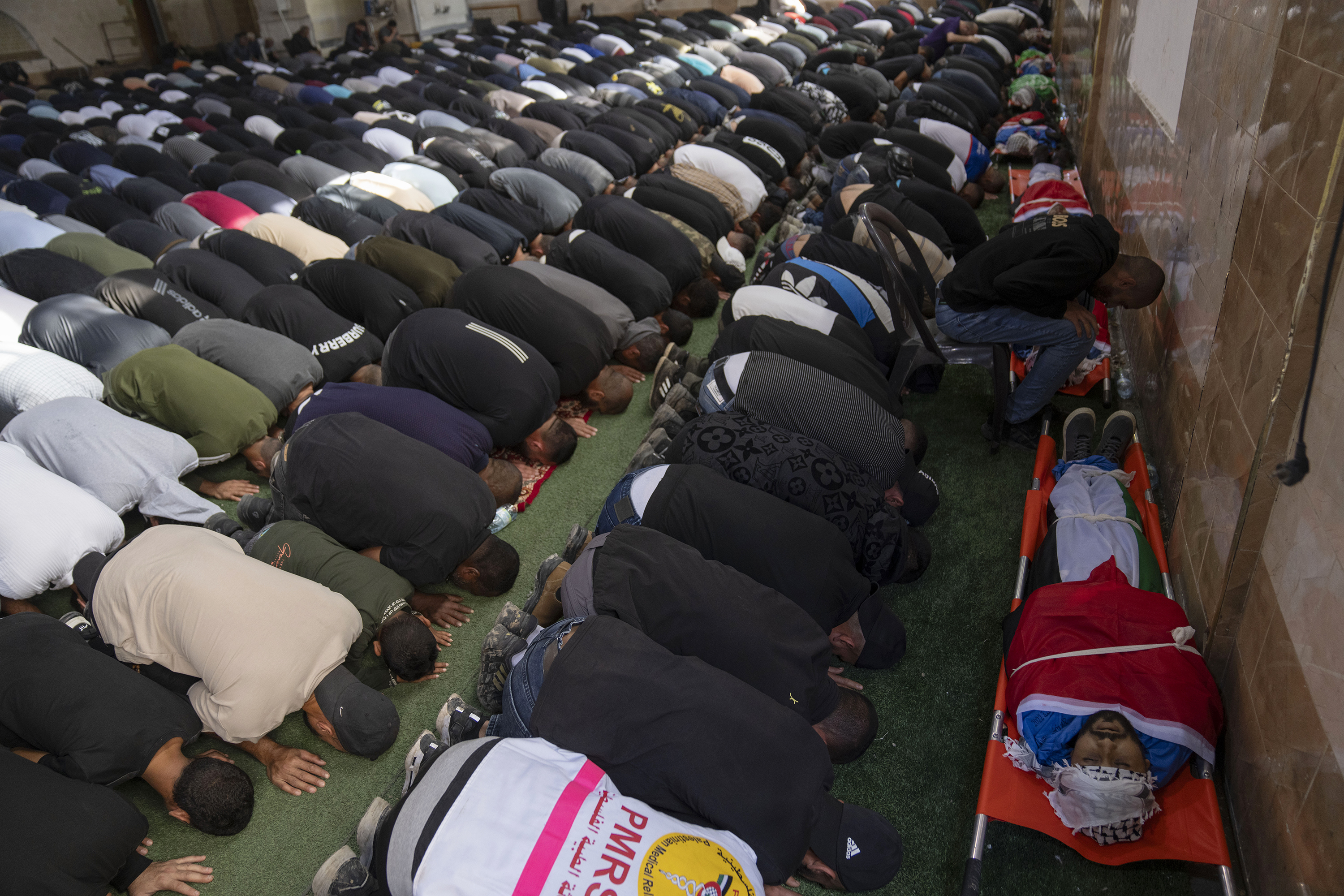 Palestinian mourners pray by the bodies of seven killed Palestinians during their funeral, in the West Bank city of TulKarem.