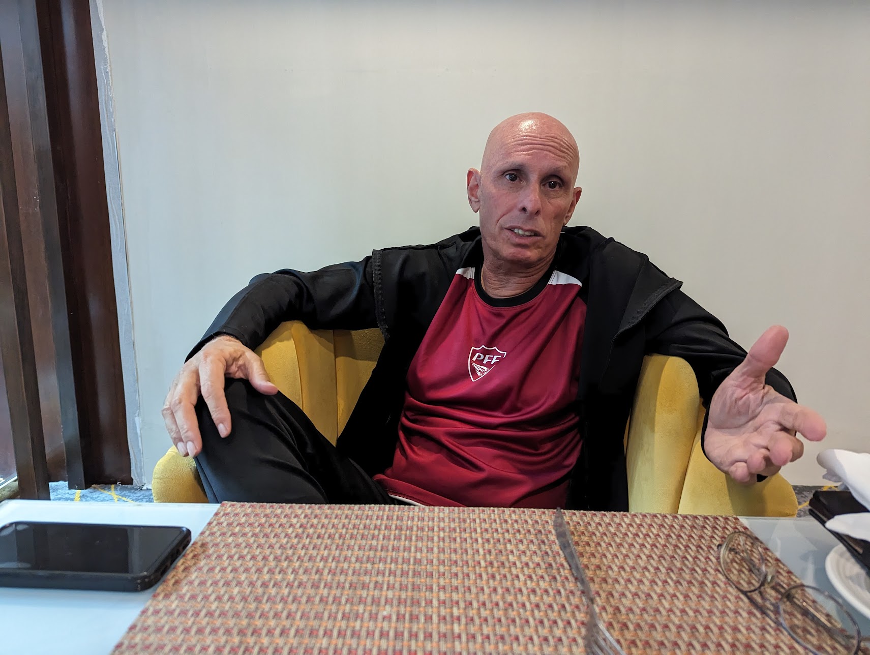 Stephen Constantine gestures while sitting behind his desk