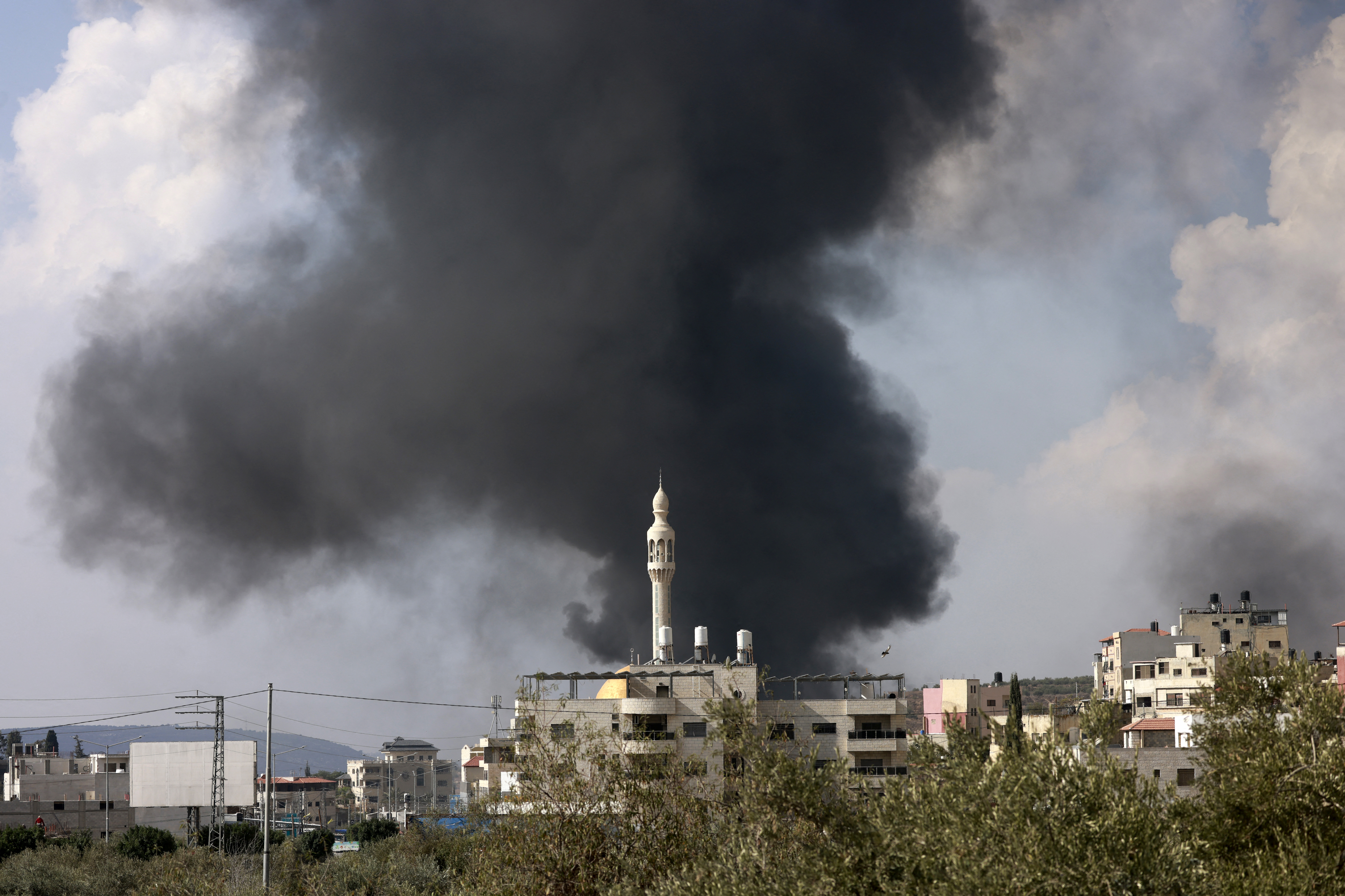 Plumes of smoke rise above the town of Deir Sharaf