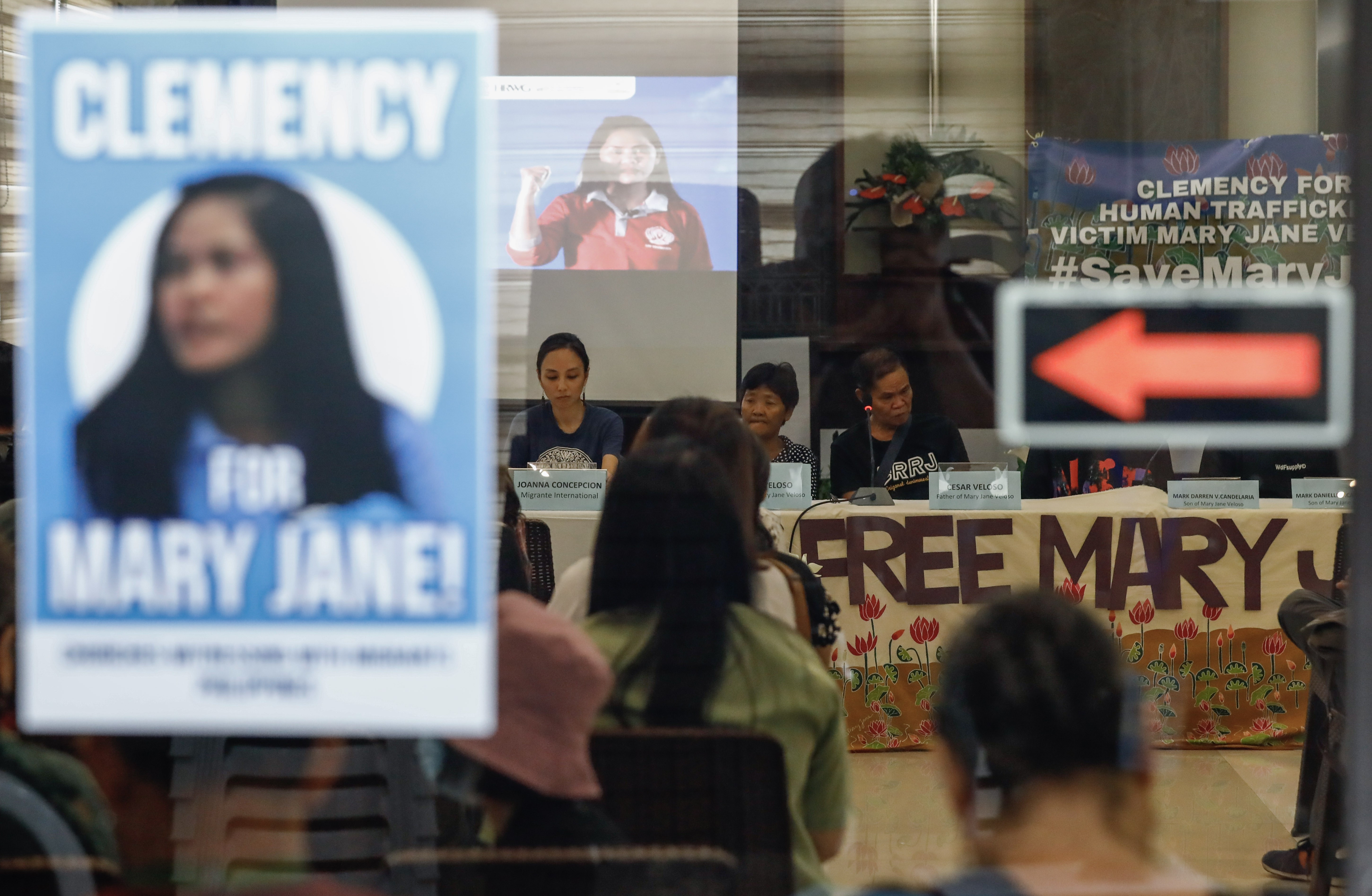 Mary Jane Veloso's parents on their visit to Indonesia earlier in June. They are seated at a table, People are holding banners calling for their daughter's freedom