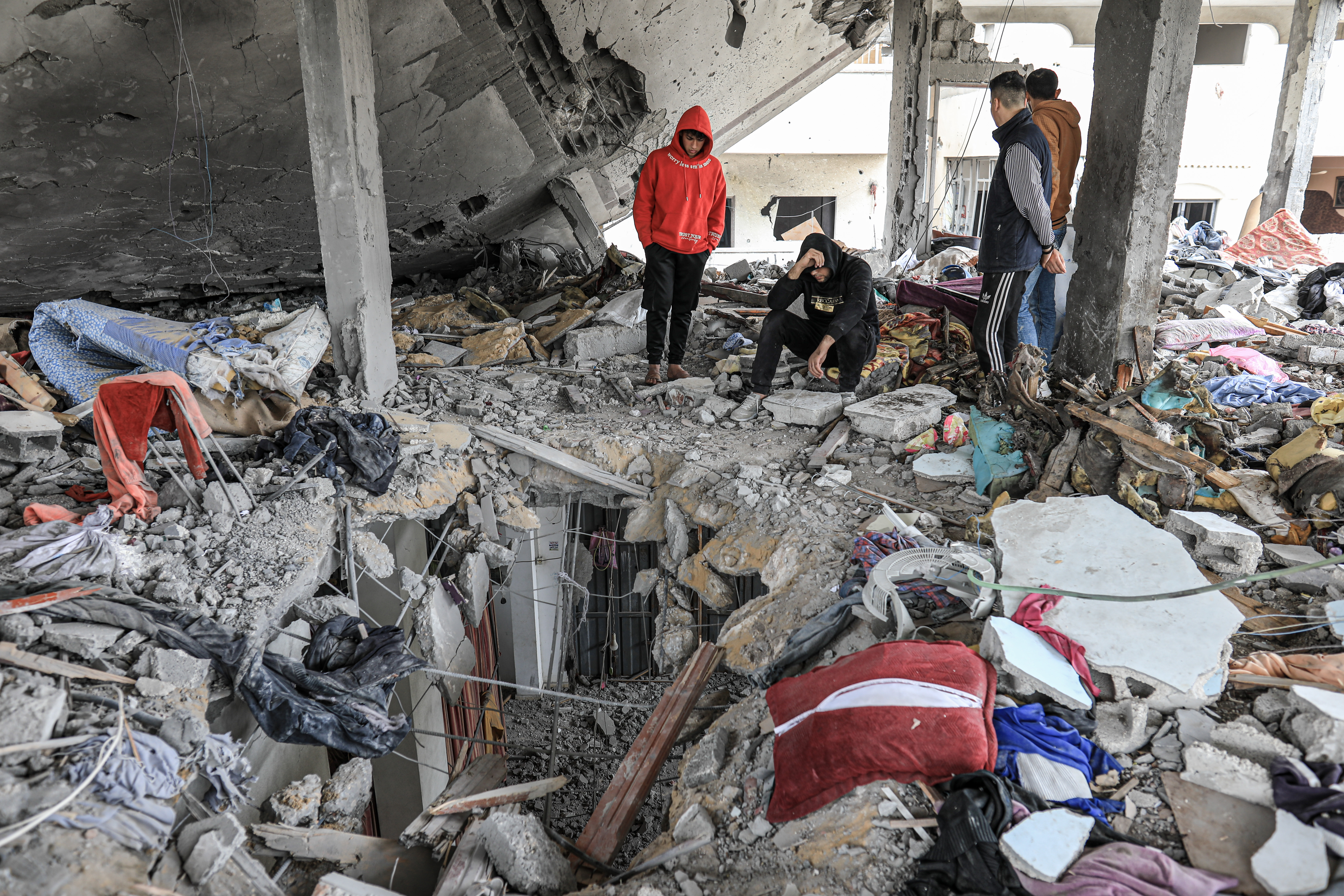 Neighbors and people sit watching the rubble of the Khalifa home in Nuseirat camp