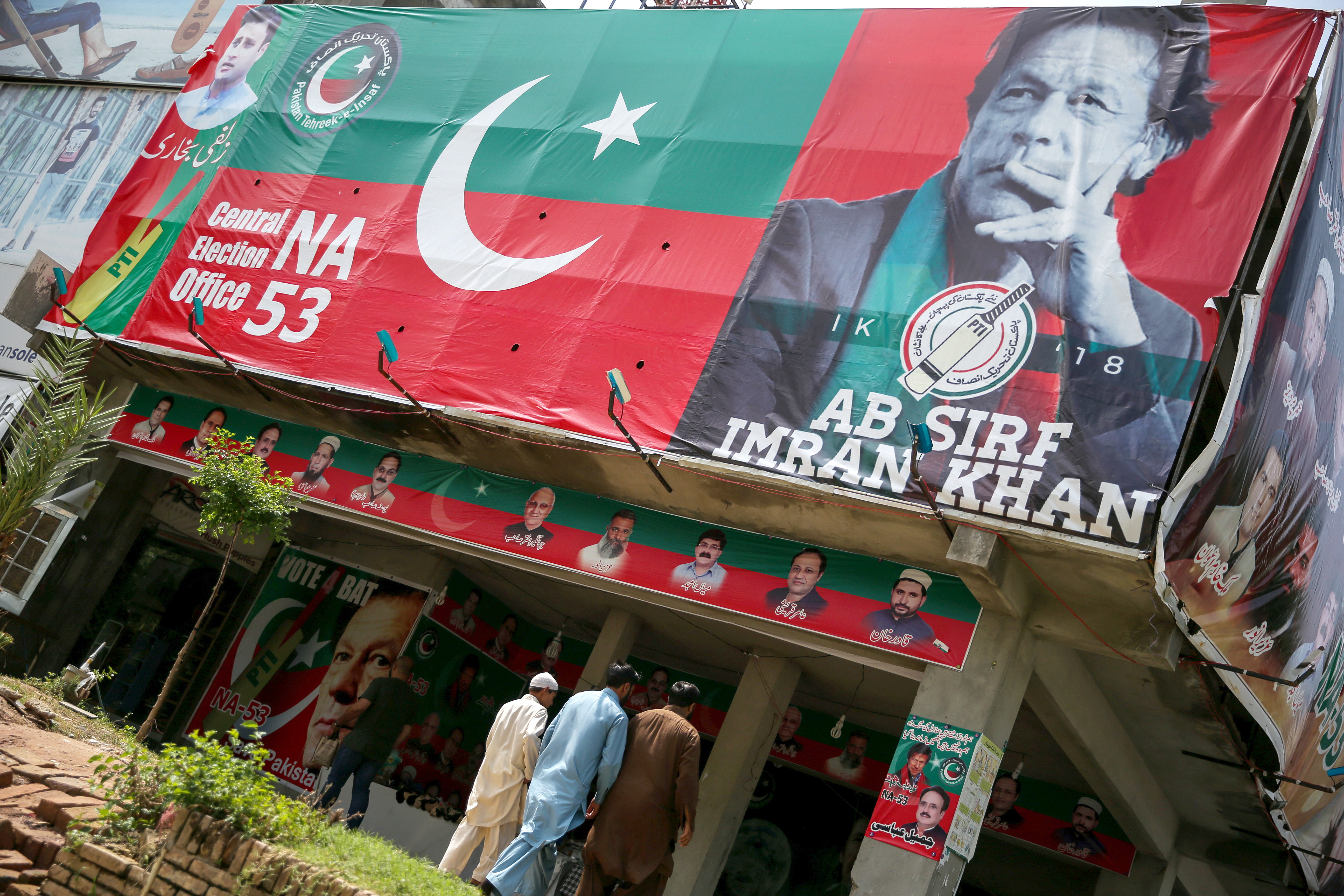 People walk past an image of cricket star-turned-politician Imran Khan, chairman of Pakistan Tehreek-e-Insaf (PTI) at a market