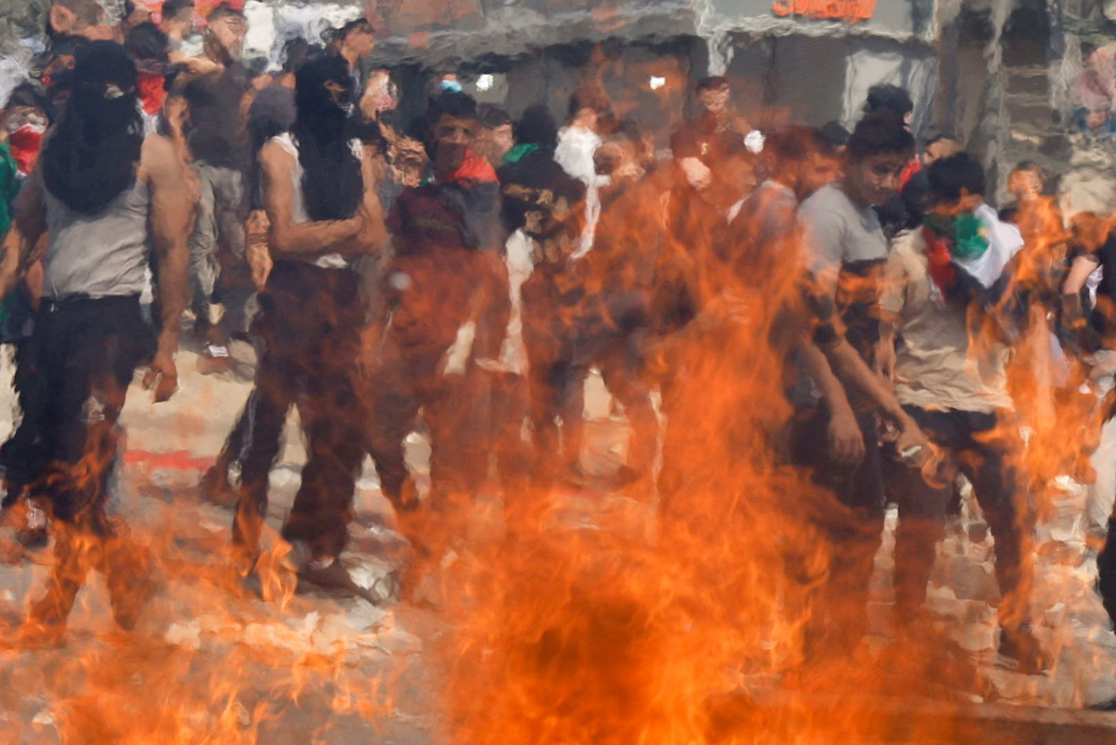 Palestinians are seen through flames during clashes with Israeli soldiers during the funeral of Palestinian Labib Dumaidi, 19, who was killed in an Israeli settlers' attack
