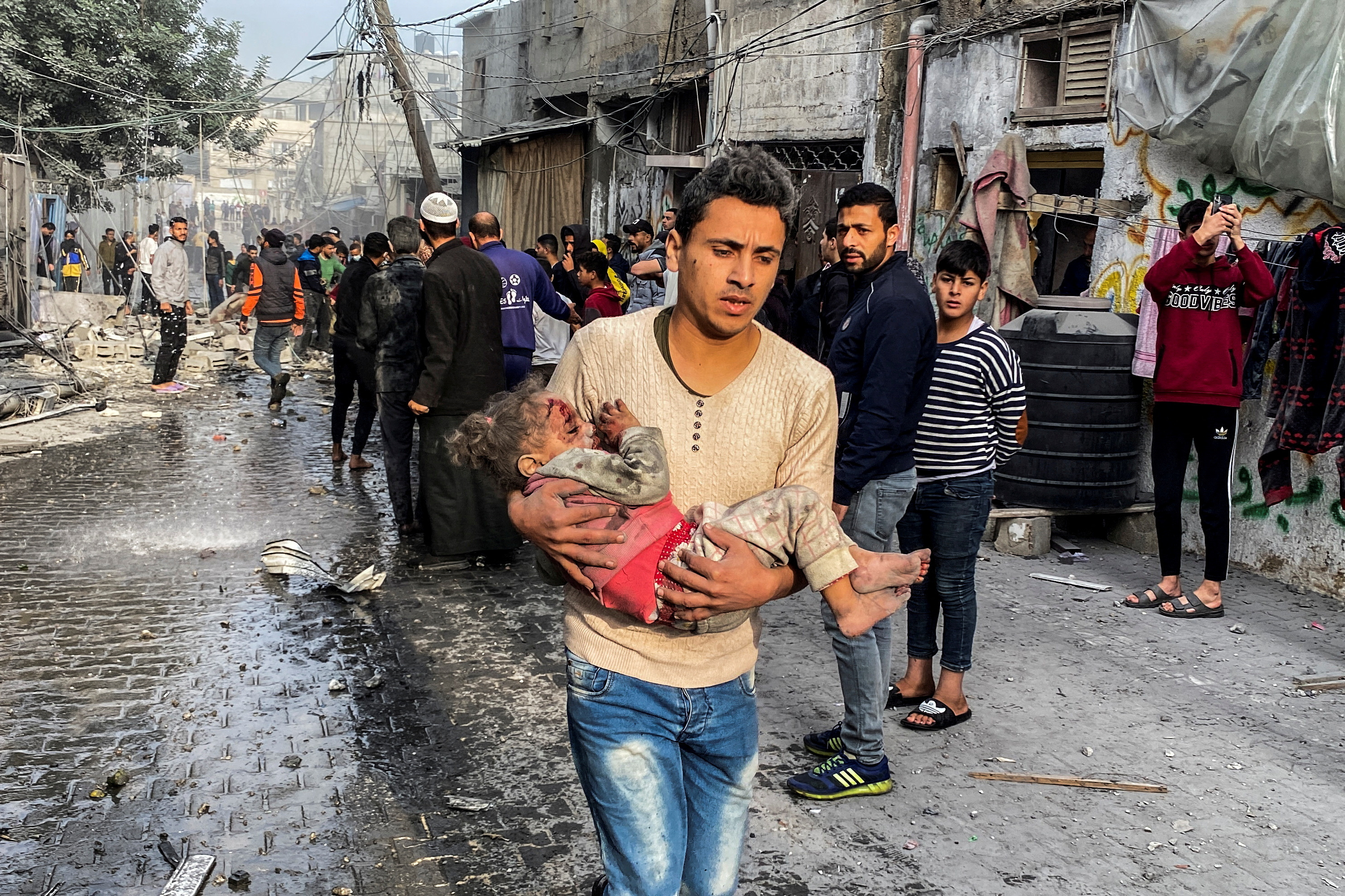 A Palestinian carries an injured child following an Israeli strike on a house, after a temporary truce between Hamas and Israel expired, in Rafah, in the southern Gaza Strip December 1, 2023.