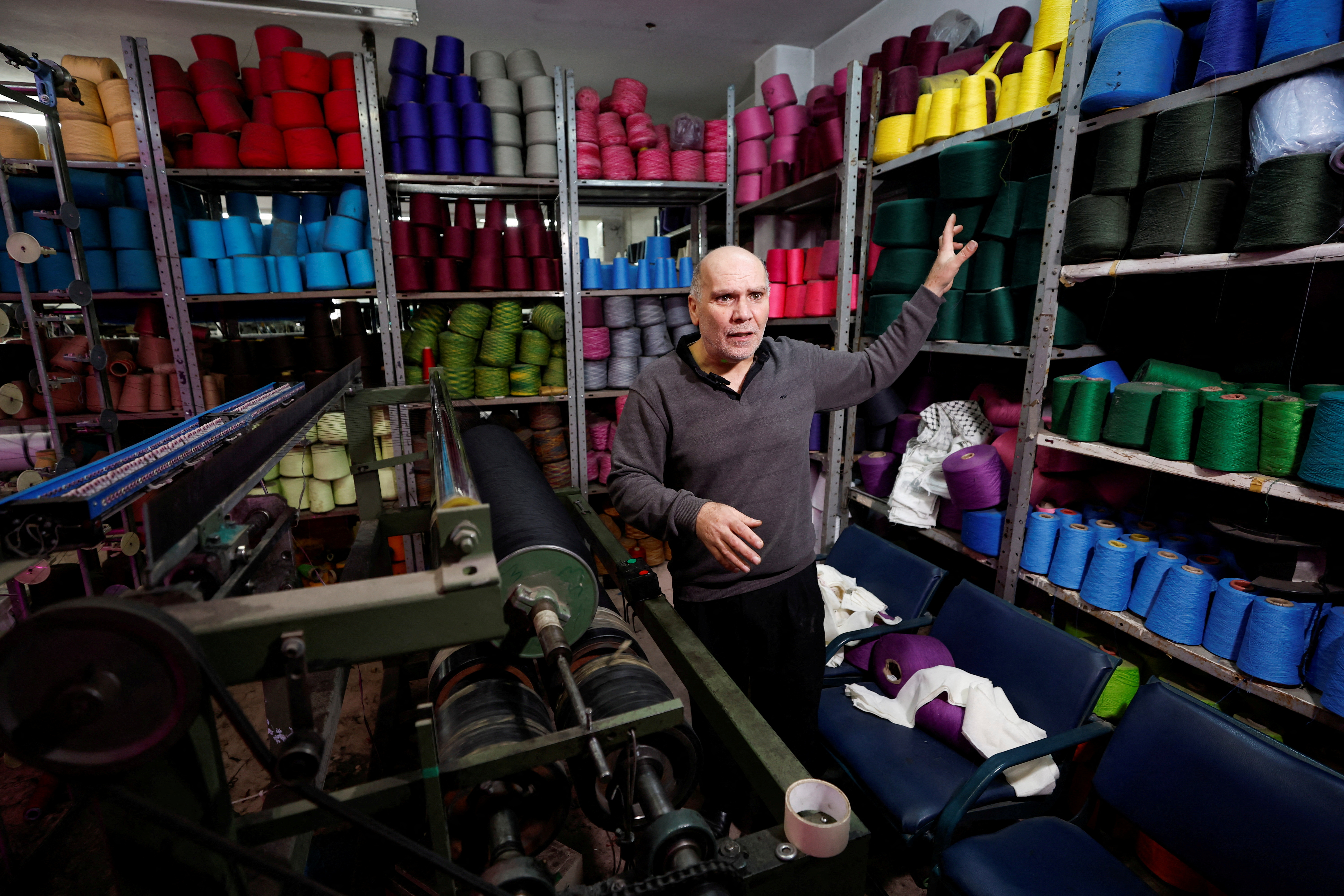 A Palestinian man shows off keffiyeh fabric of various colours in a shop