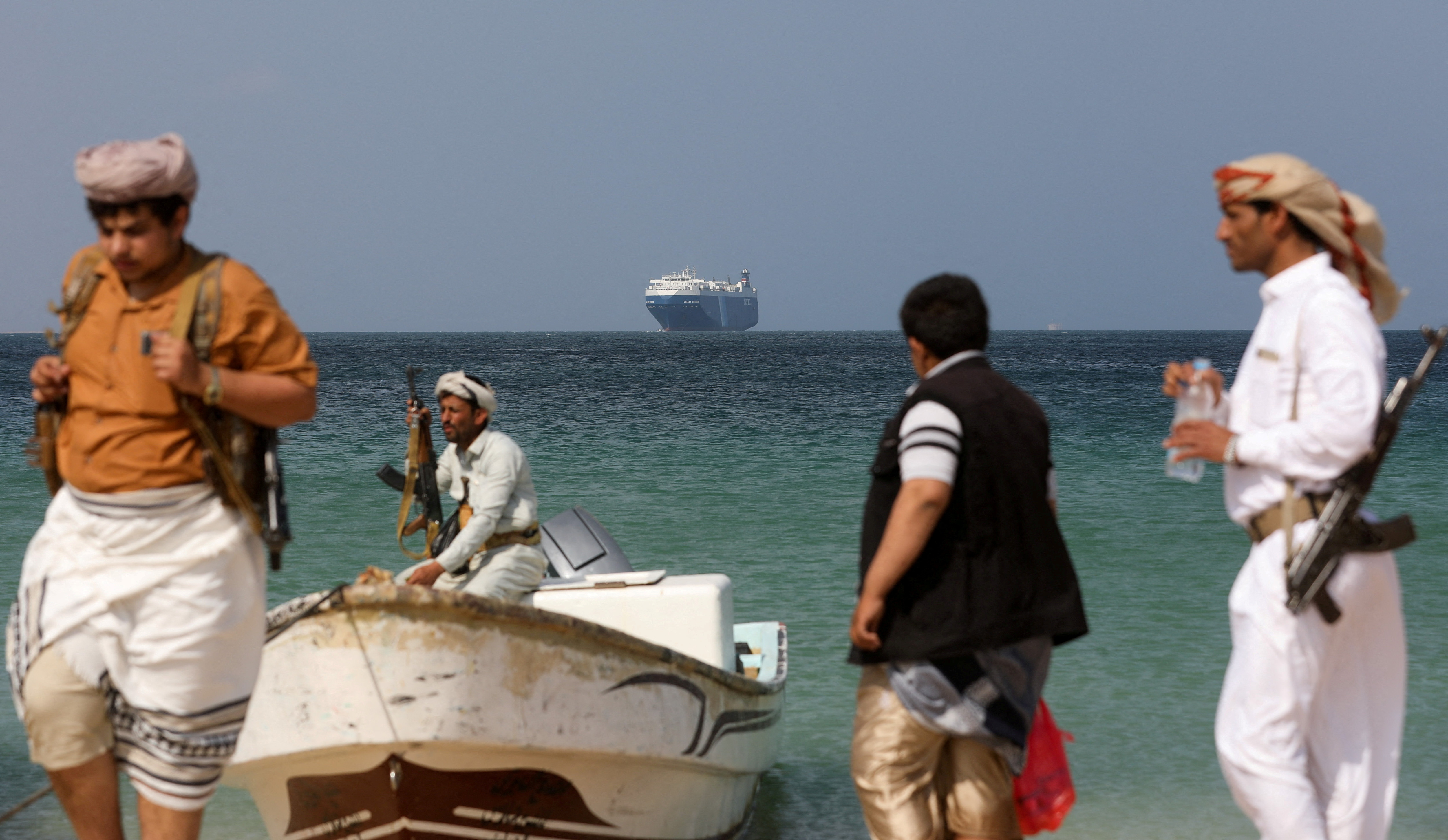 Armed men on the beach in Yemen. A large ship can be seen in the sea behind them.