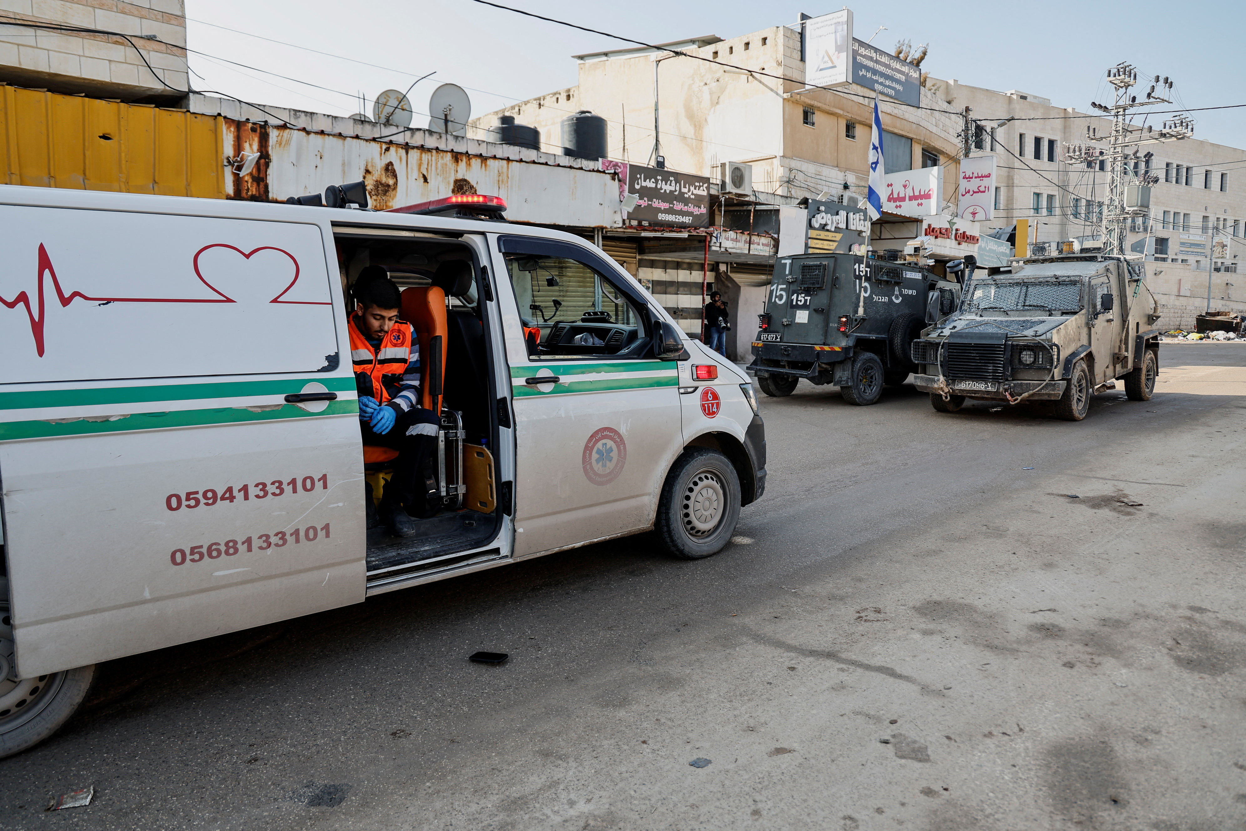 An emergency worker sits in an ambulance blocked by Israeli military vehicles during a raid, amid the ongoing conflict between Israel and the Palestinian Islamist group Hamas, in Jenin,