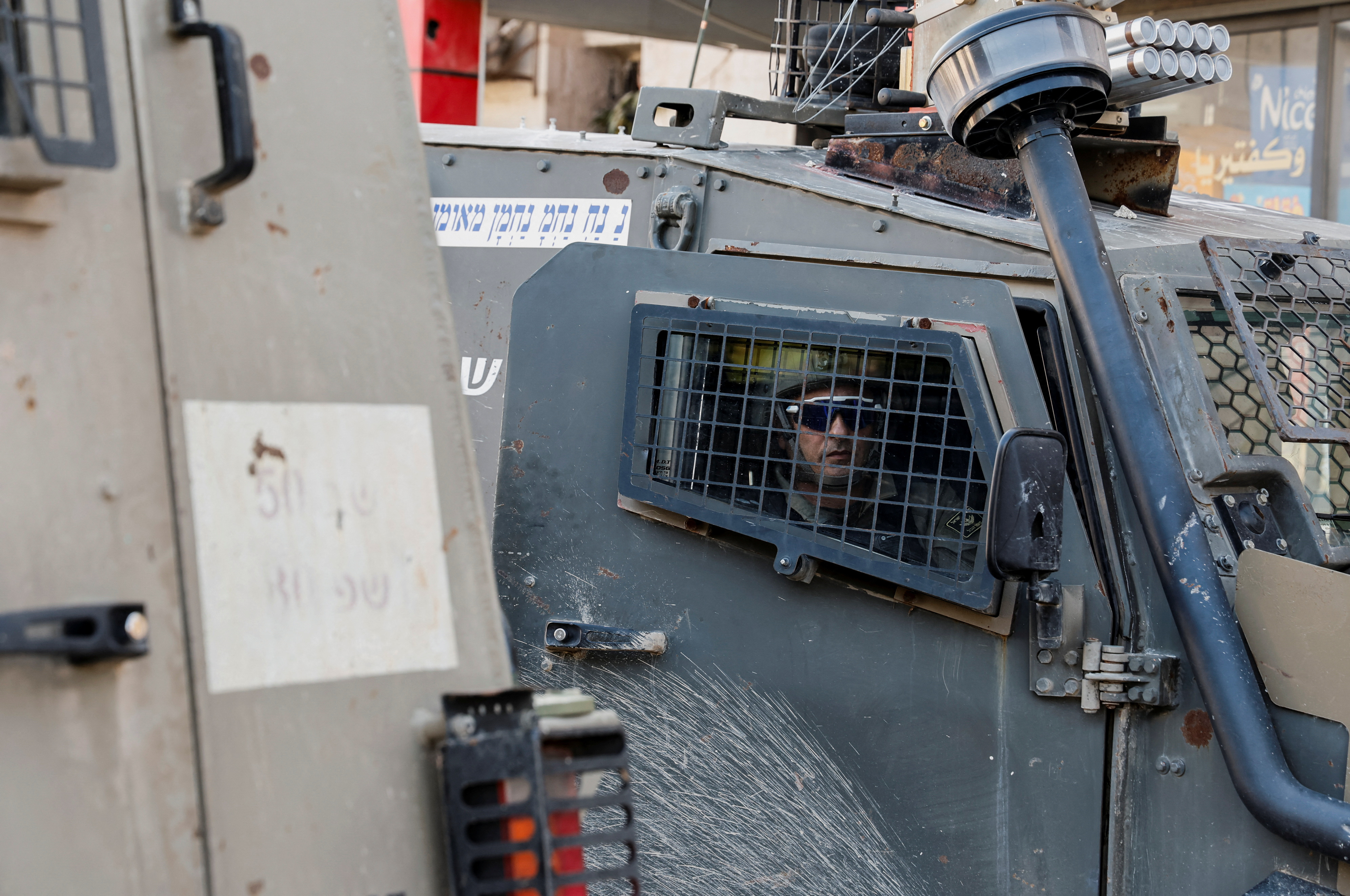 An Israeli soldier looks on from inside a military vehicle during a raid,