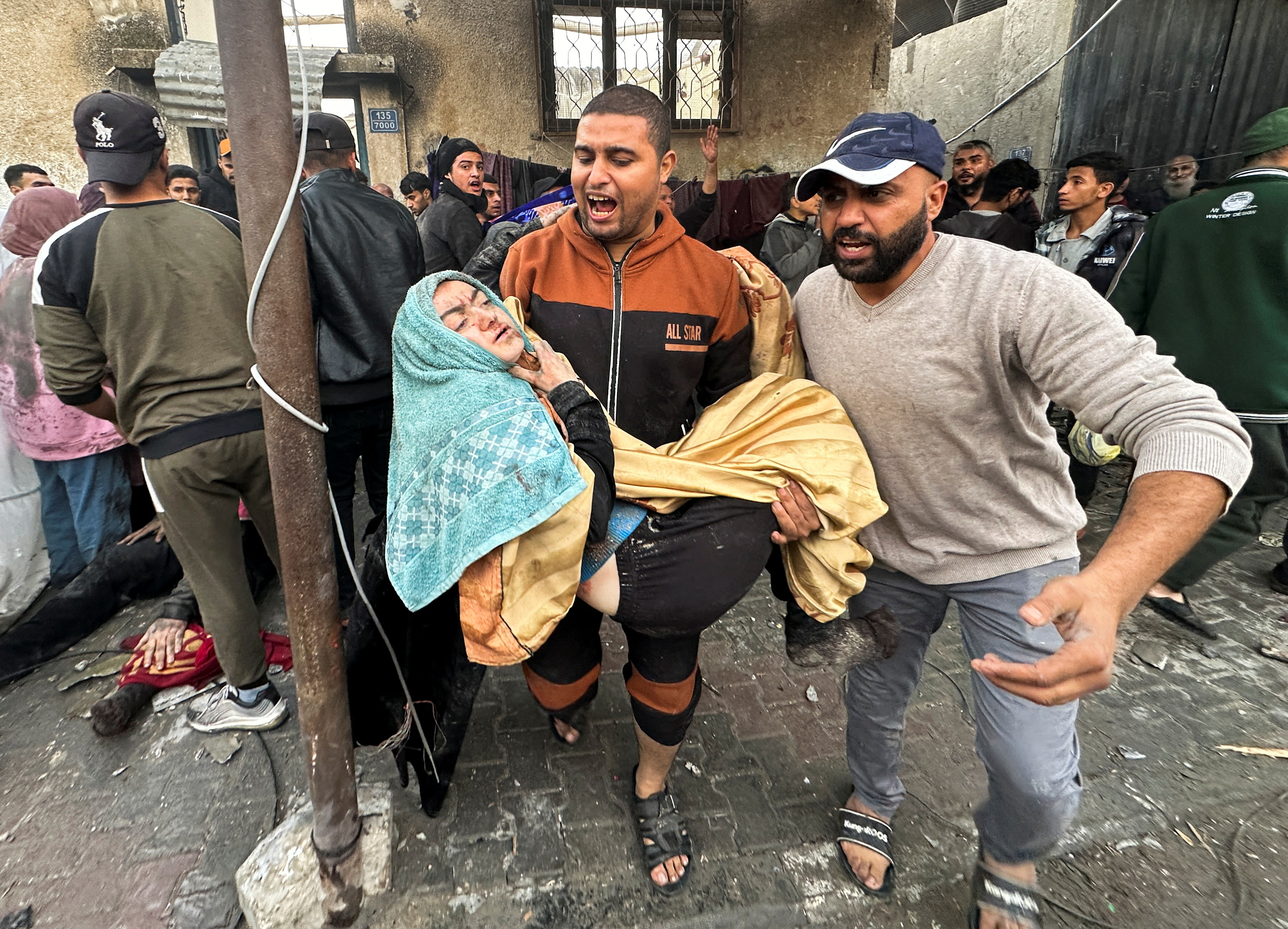 People carry an injured person following an Israeli air strike on Palestinian houses, amid the ongoing conflict between Israel and the Palestinian Islamist group Hamas, in Rafah in the southern Gaza Strip December 12
