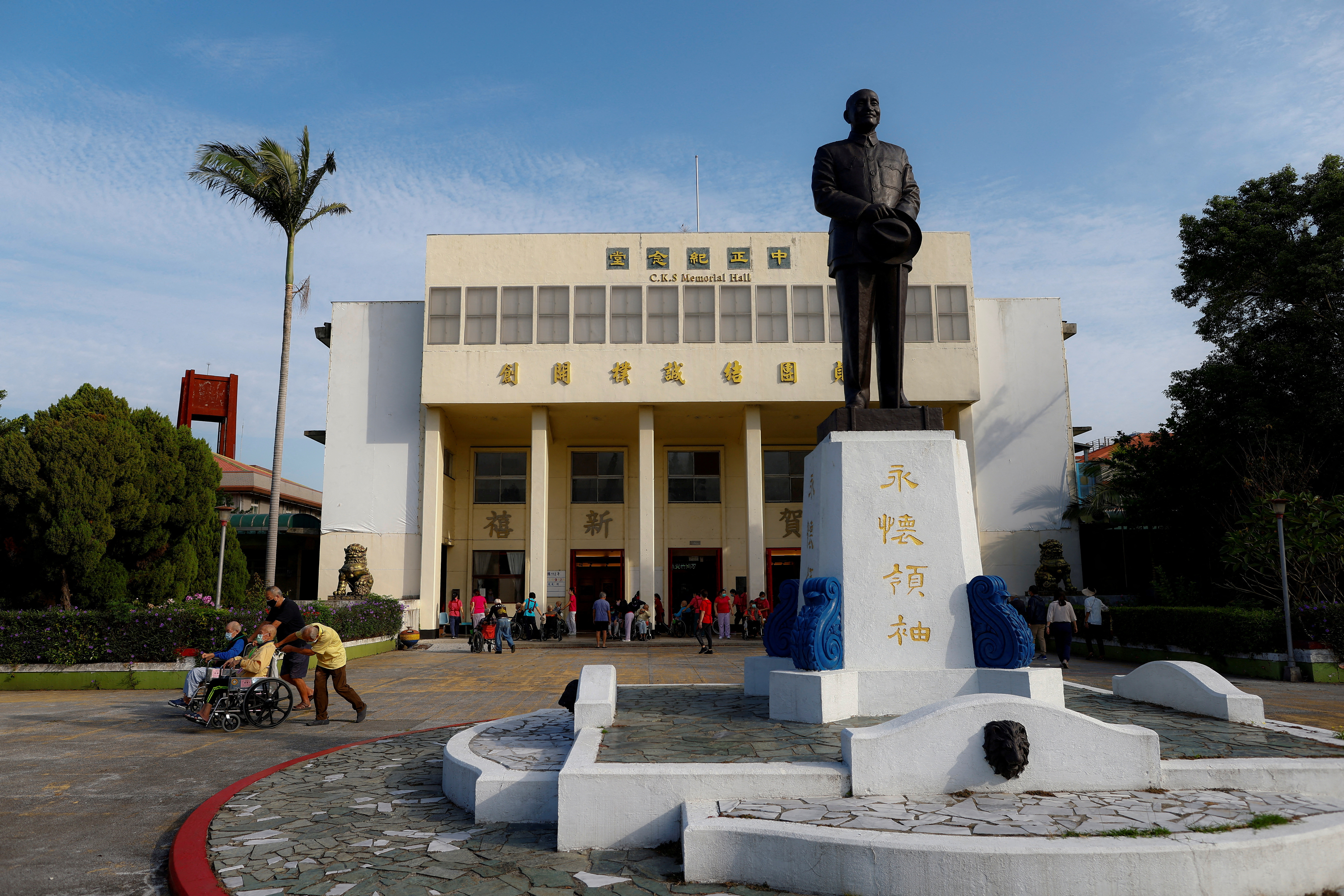 Care workers push residents of Taoyuan Veterans Home in wheelchairs next to a statue of Taiwan's former President Chiang Kai-shek, after a morning workout in Taoyuan, Taiwan.
