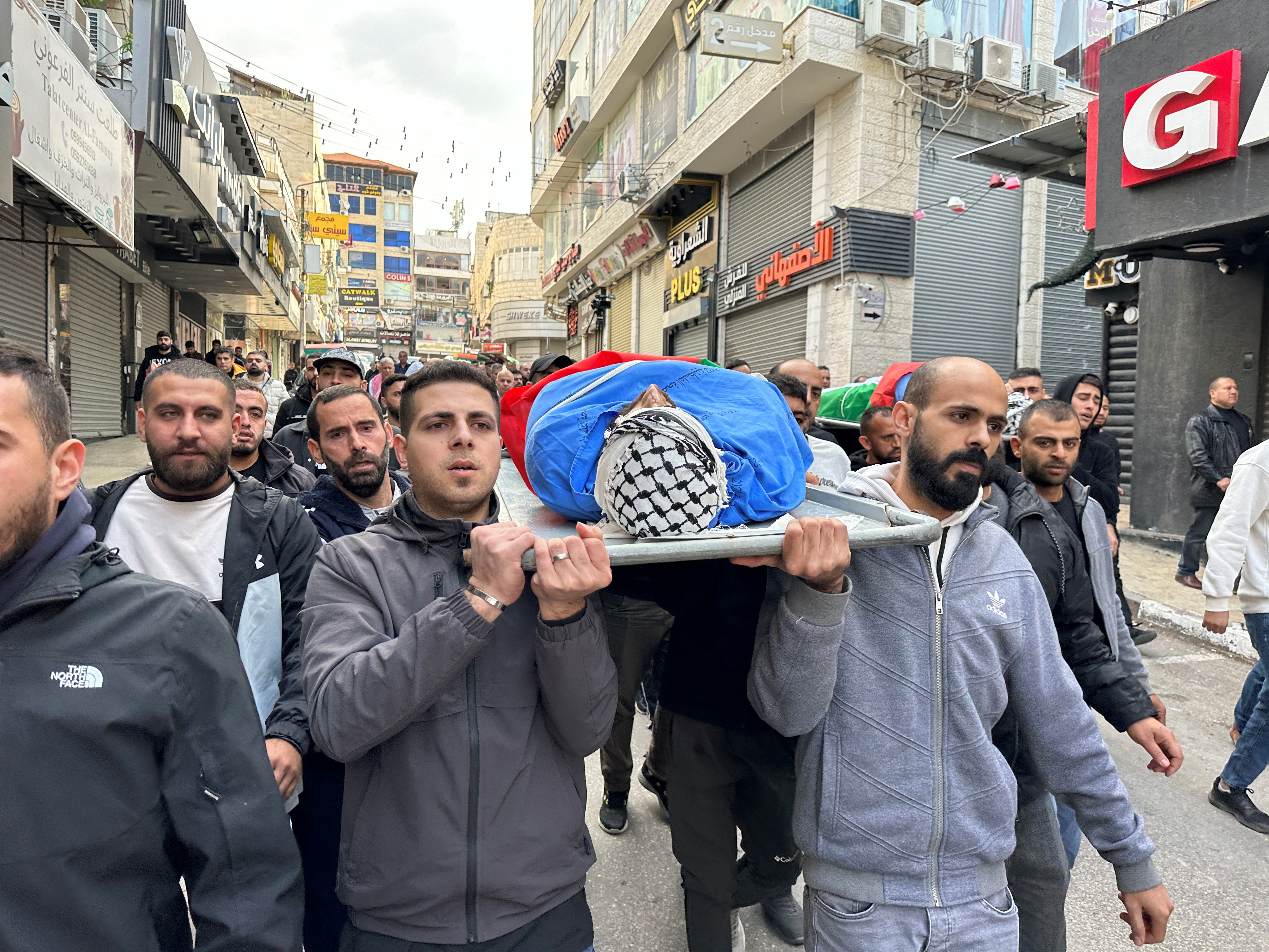 Mourners carry the bodies of Palestinians who were killed during an Israeli raid in the occupied West Bank