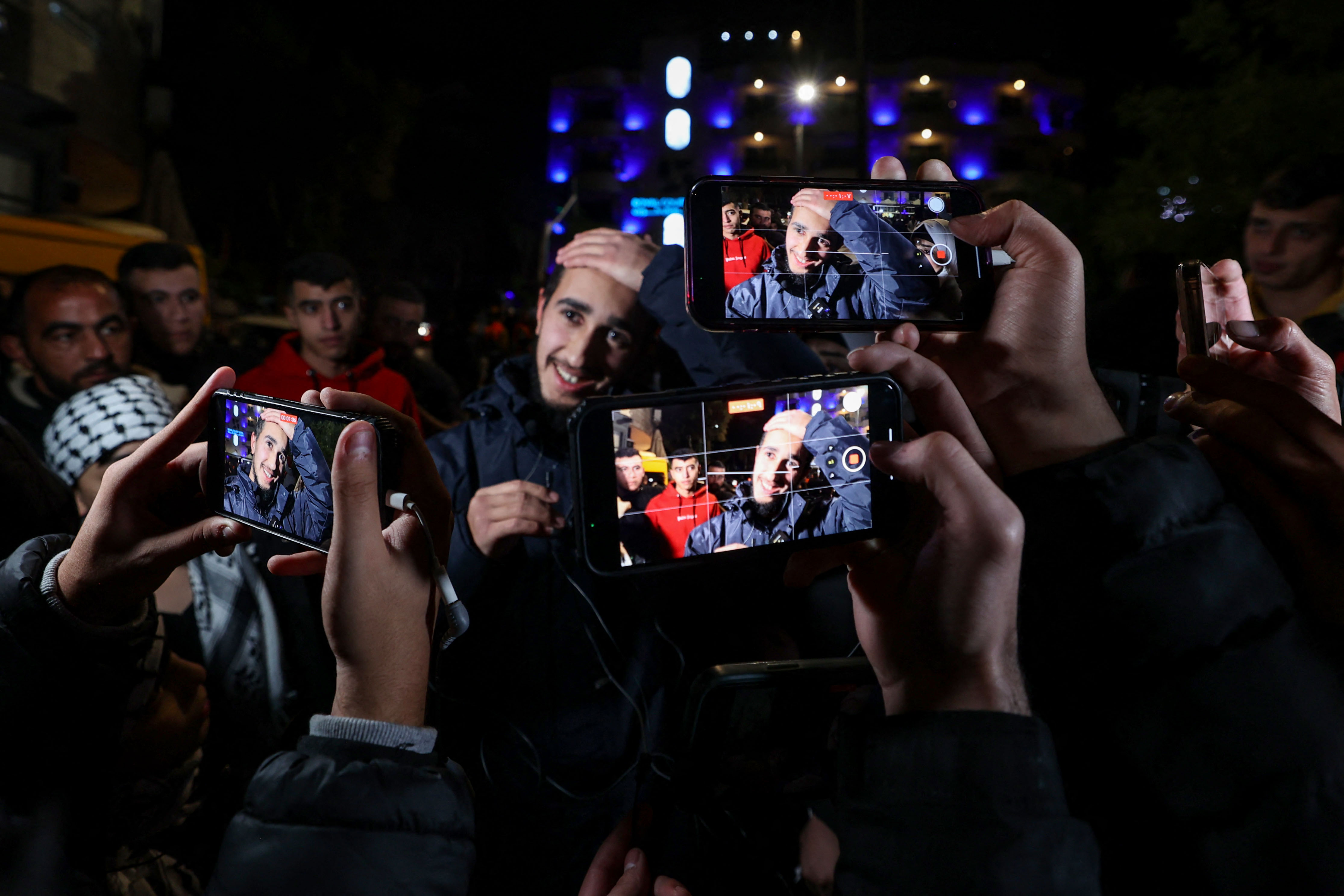 A newly released prisoner gestures amid supporters holding phones during a welcome ceremony following the release of Palestinian prisoners from Israeli jails.