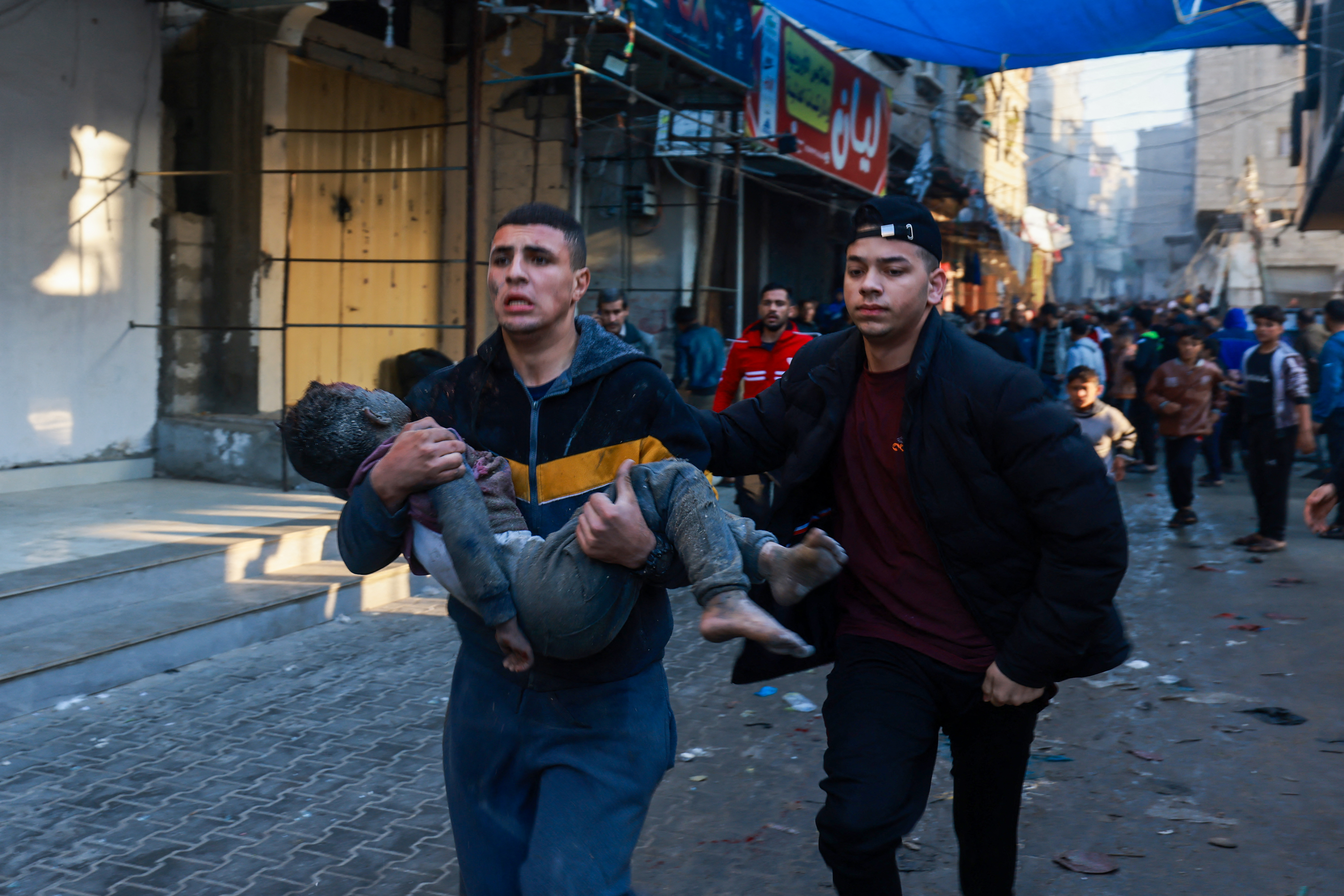 A Palestinian man holds a child as they flee following the resumption of Israeli bombardment in Rafah