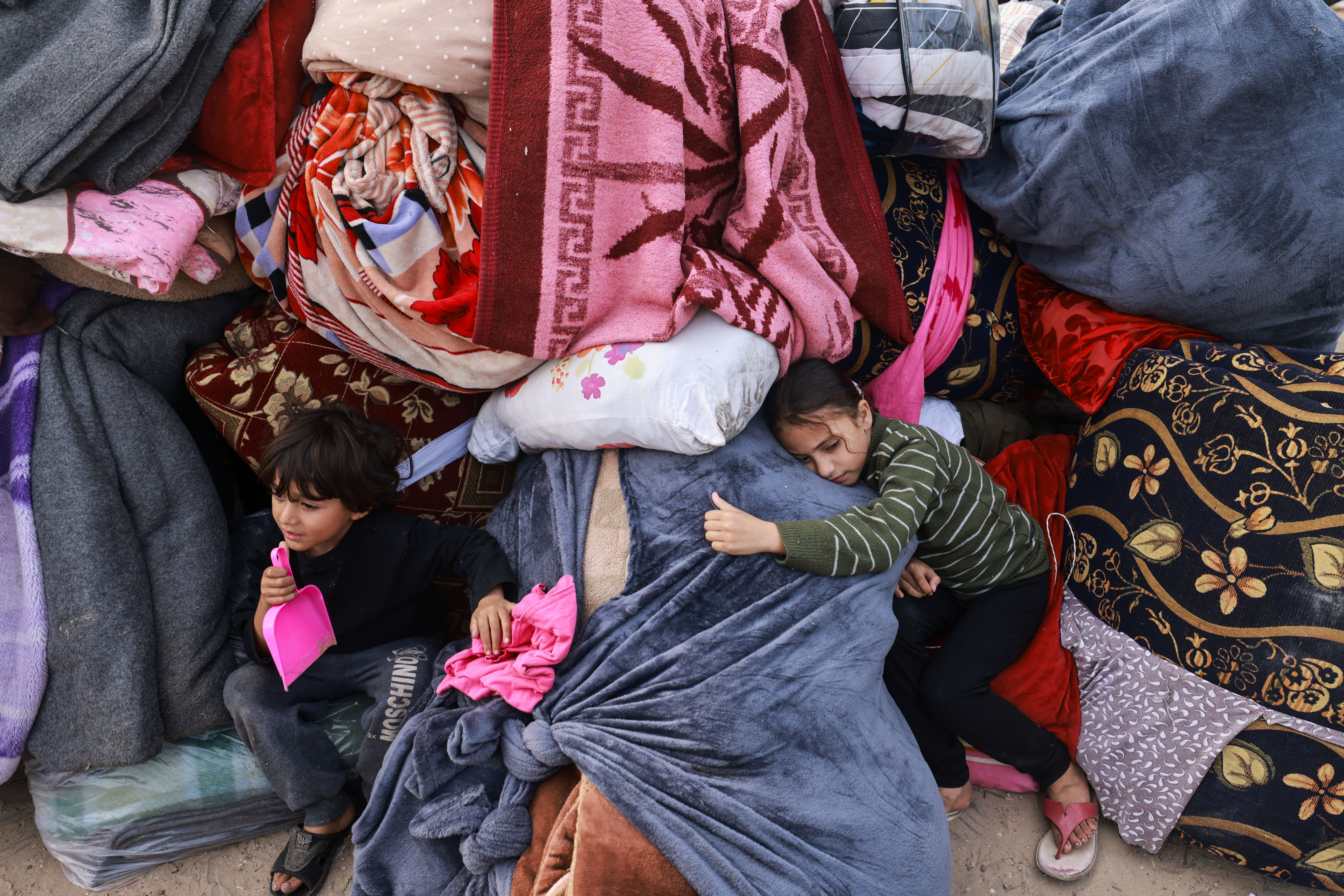 Children rest on blankets as displaced Palestinians fleeing central and southern Gaza set up tents in the new Tall el-Sultan camp west of Rafah in the southern Gaza Strip.