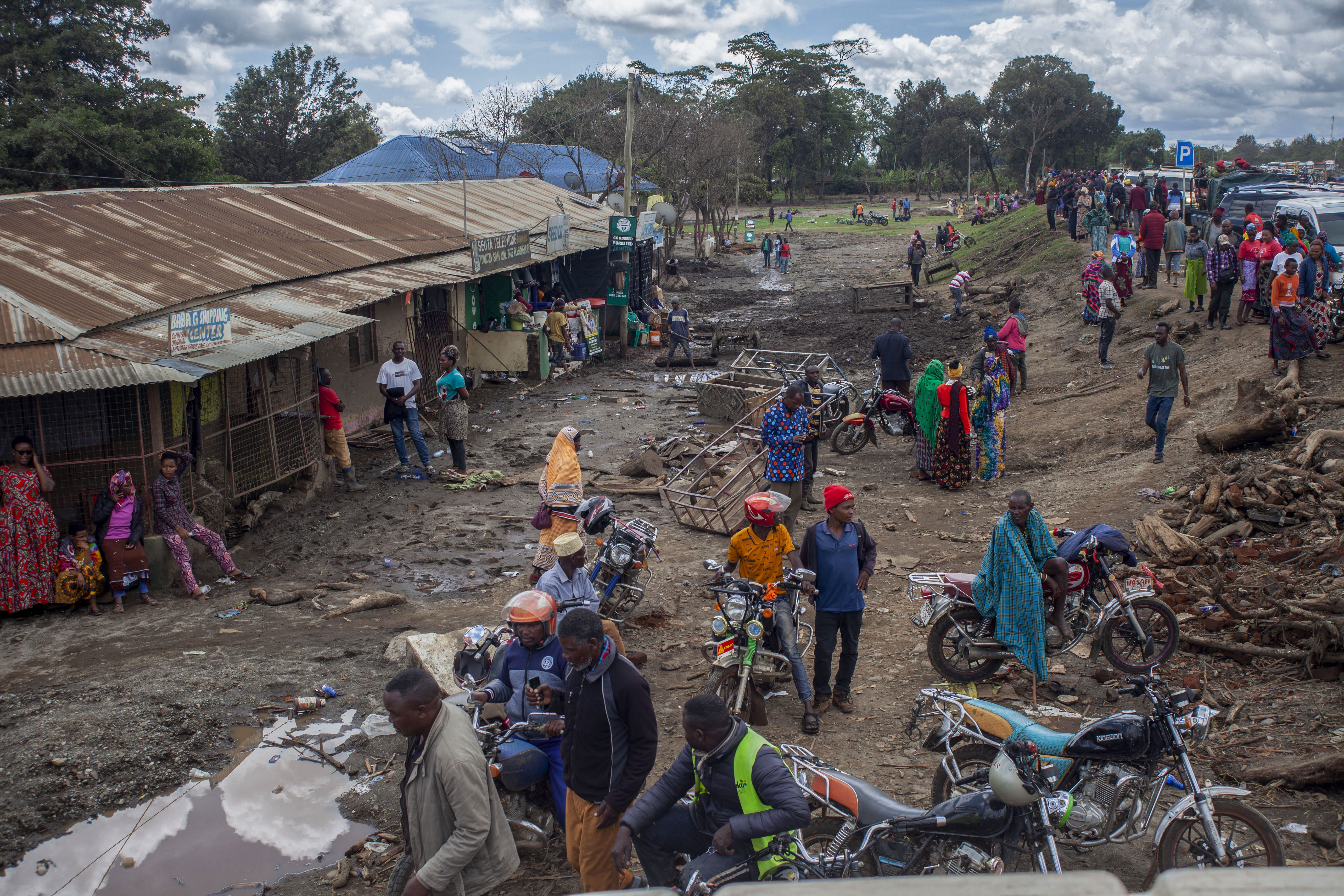 People gather to assess damages at a street covered on mud following landslides and flooding triggered by heavy rainfall in Katesh, Tanzania.