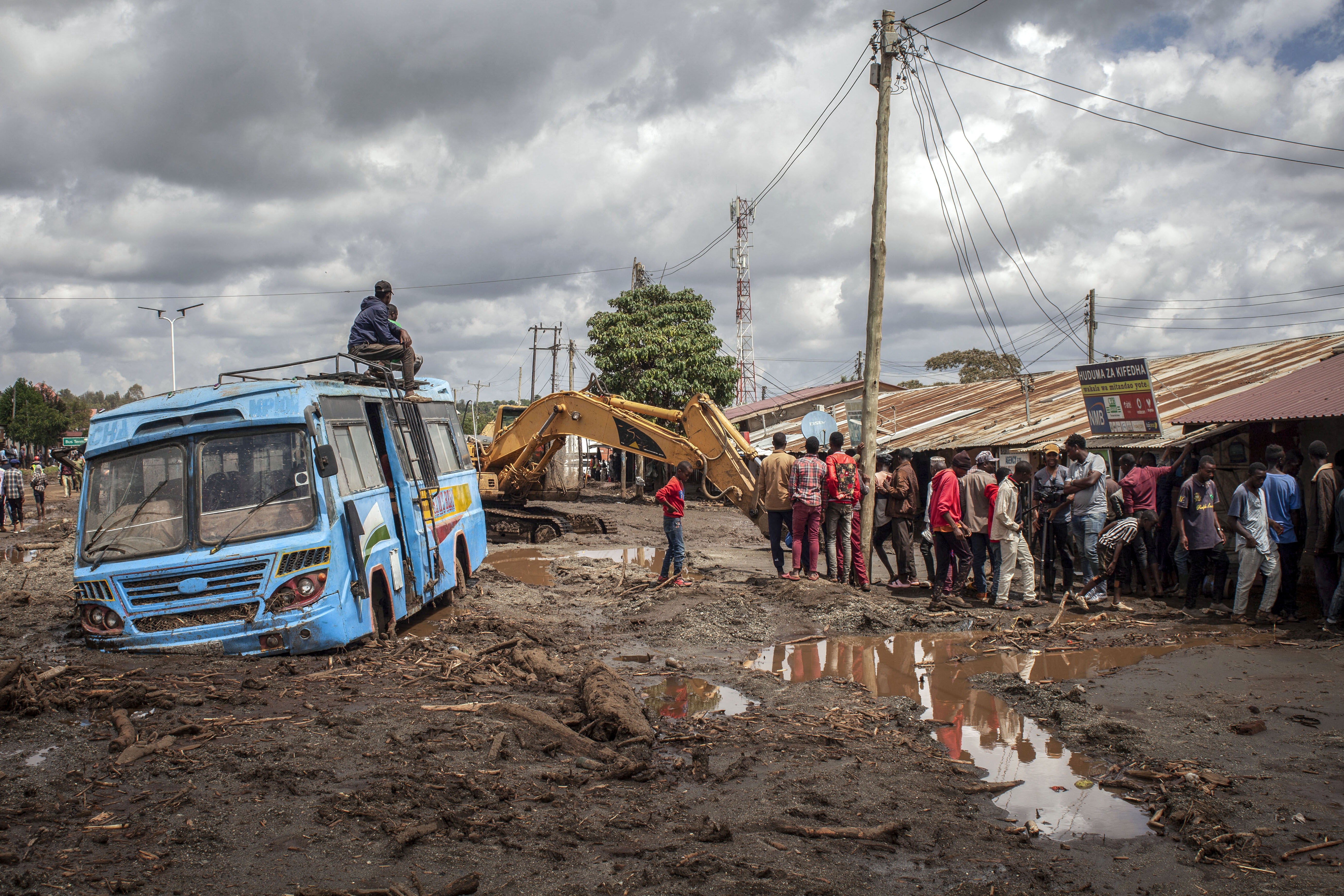 People gather to assess damages at a street covered on mud following landslides and flooding triggered by heavy rainfall in Katesh, Tanzania.