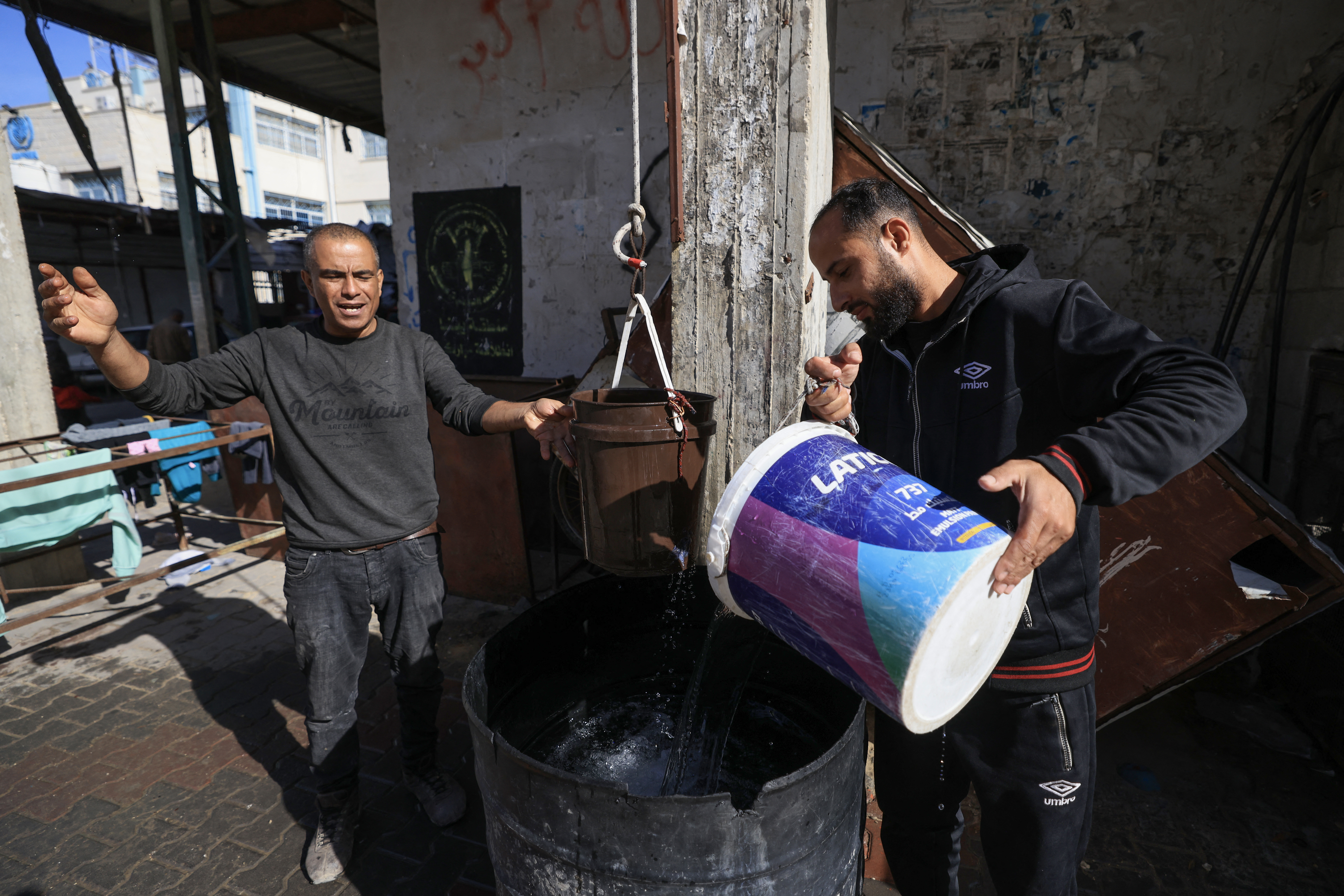 People lift water with a pulley and rope to the roof of a building in Rafah in the southern Gaza Strip on December 9