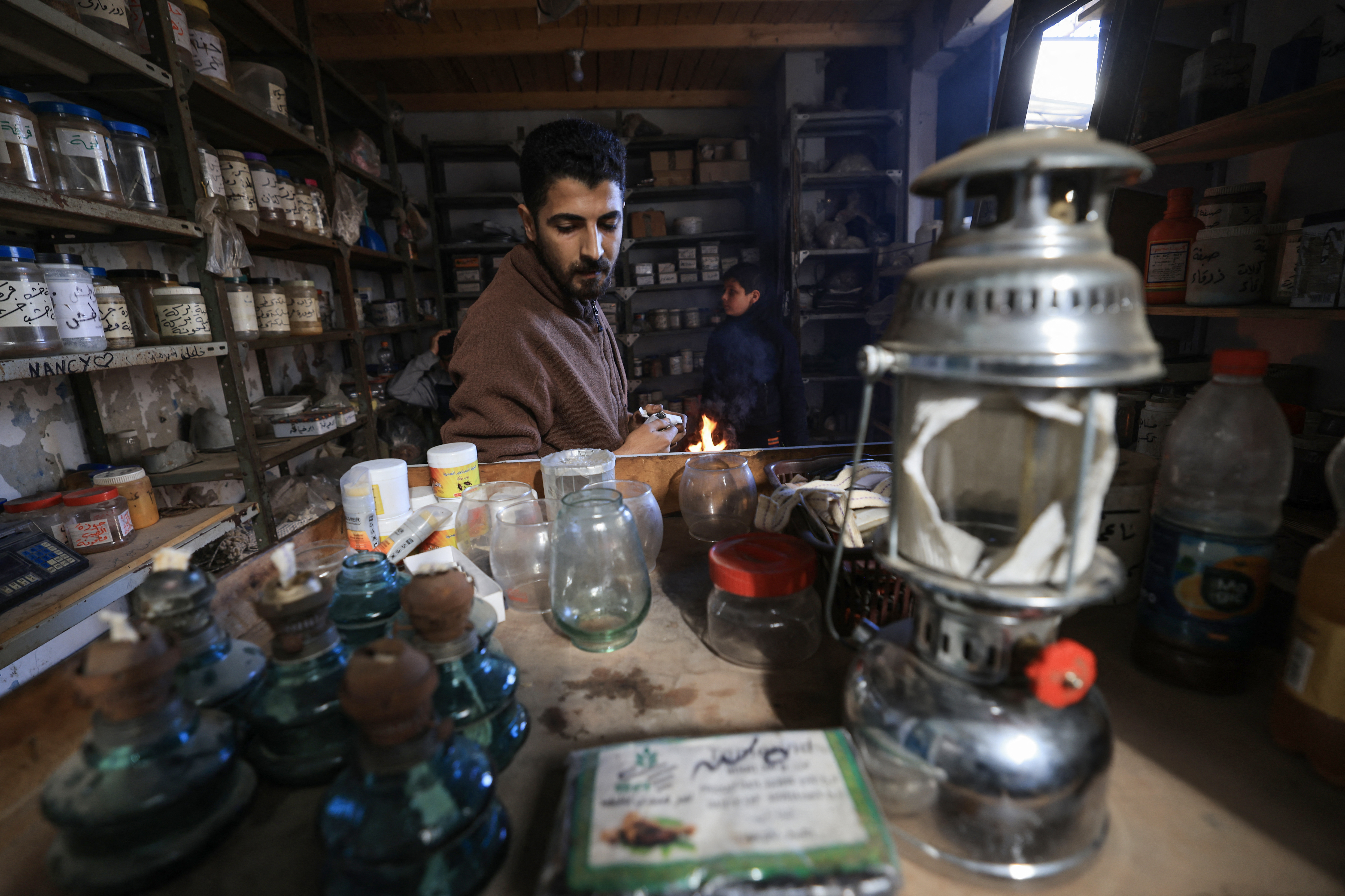 People who fled Khan Yunis in the southern Gaza Strip to Rafah further south, cook in the street near where they found temporary shelter, on December 9