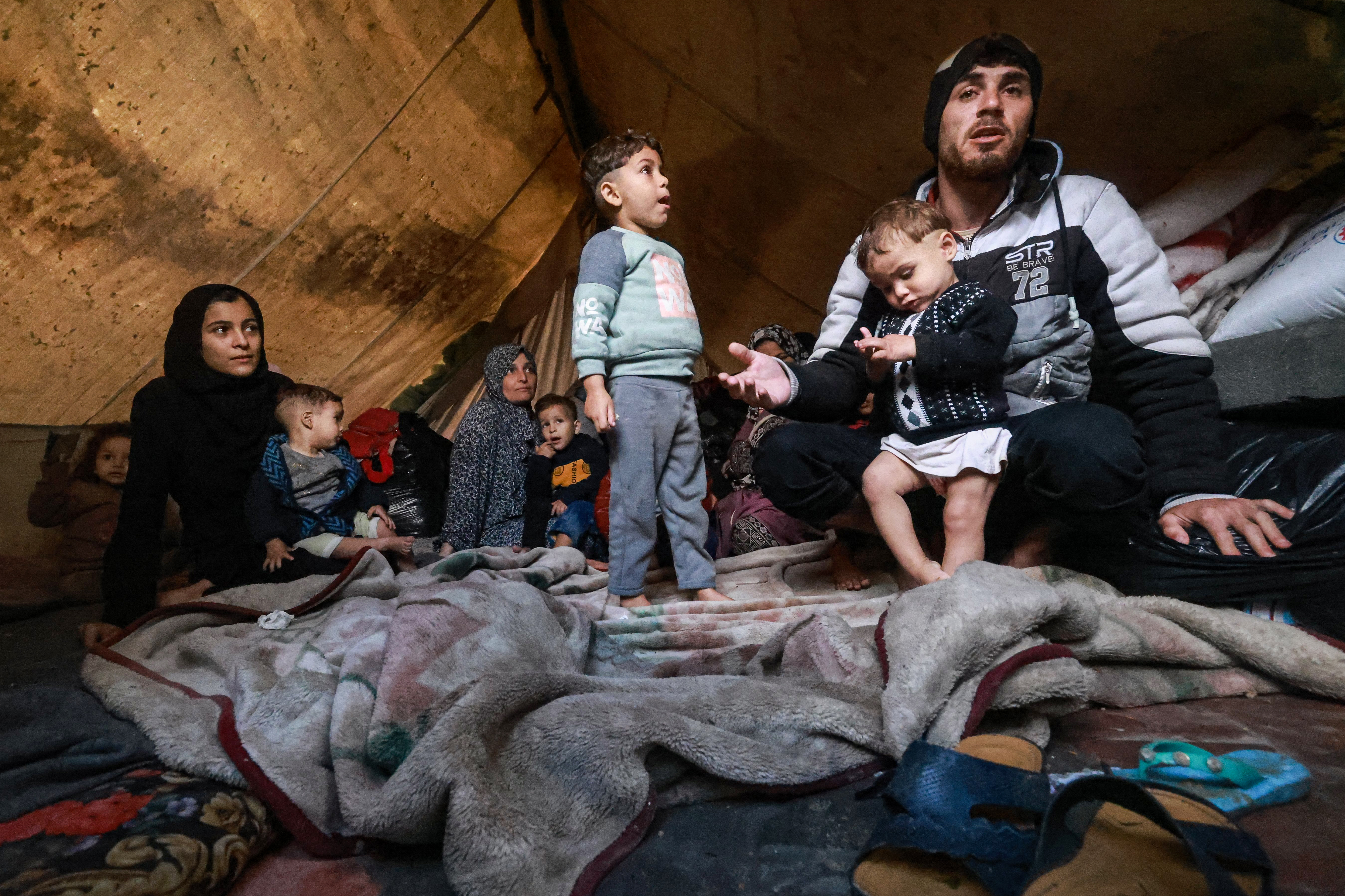 Palestinians rest in their makeshift tent at a camp set up on a schoolyard in Rafah in the southern Gaza Strip where most civilians have taken refuge.
