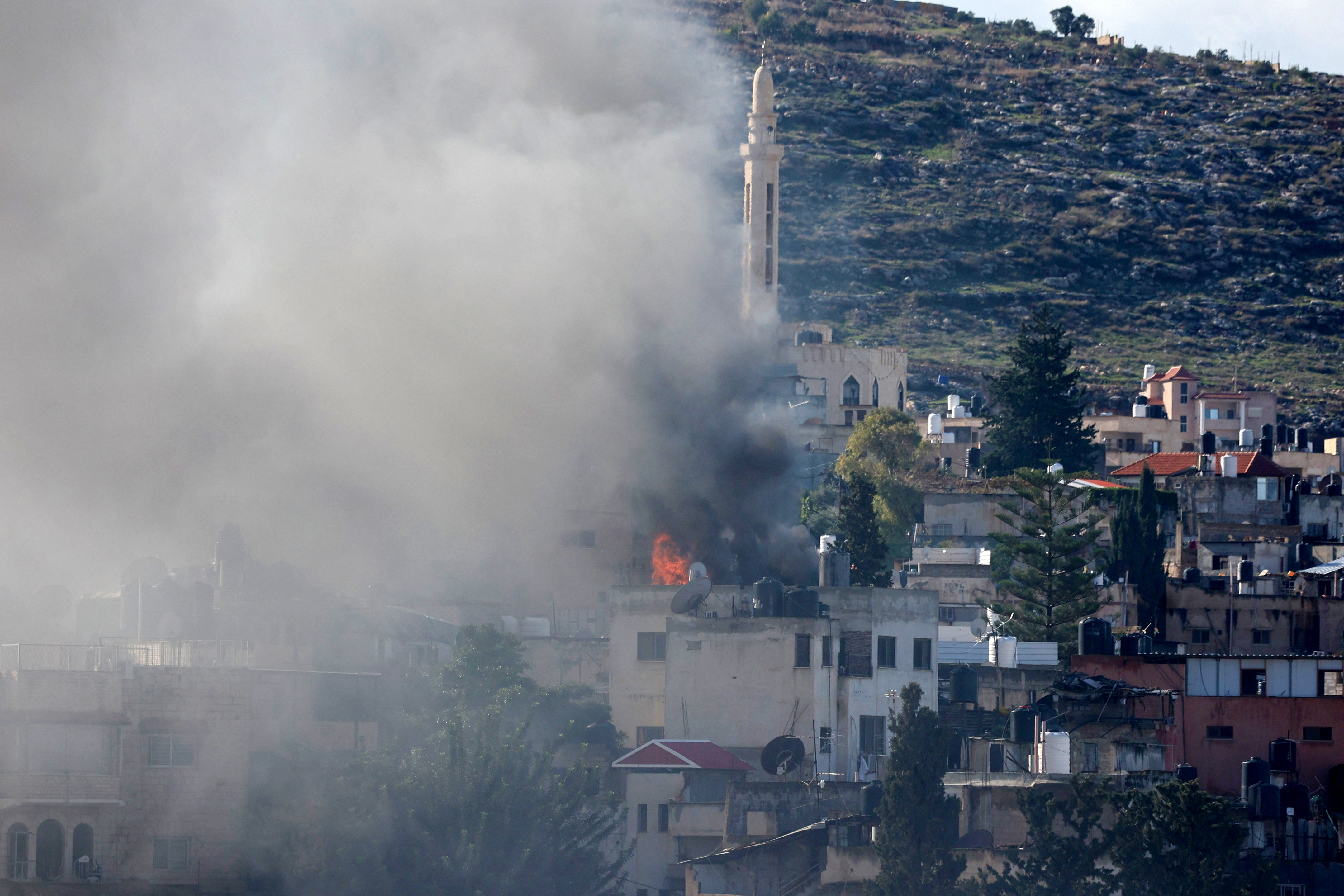 Smoke billows following an explosion which targeted a house that the Israeli army said belonged to a suspect during the military operation inside the Jenin refugee camp. [Jaafar Ashtiyeh/AFP
