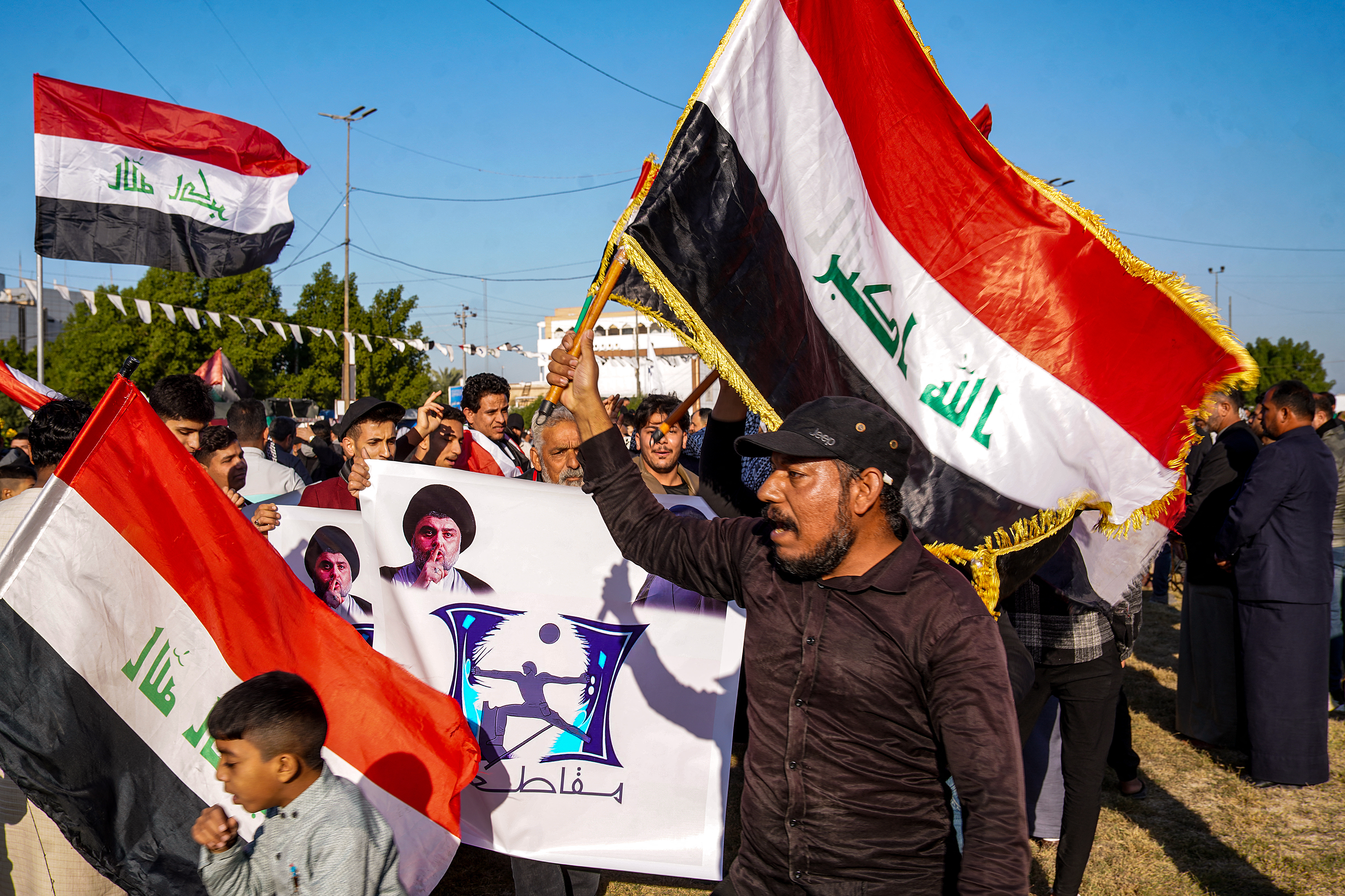 A supporter of Shiite Muslim cleric Muqtada al-Sadr marches with an Iraqi national flag with others during a protest reiterating his call to boycott of the upcoming 2023 Iraqi municipal elections scheduled for December 18, in Iraq's central holy shrine city off Najaf on December 14, 2023. (Photo by Qassem al-KAABI / AFP)
