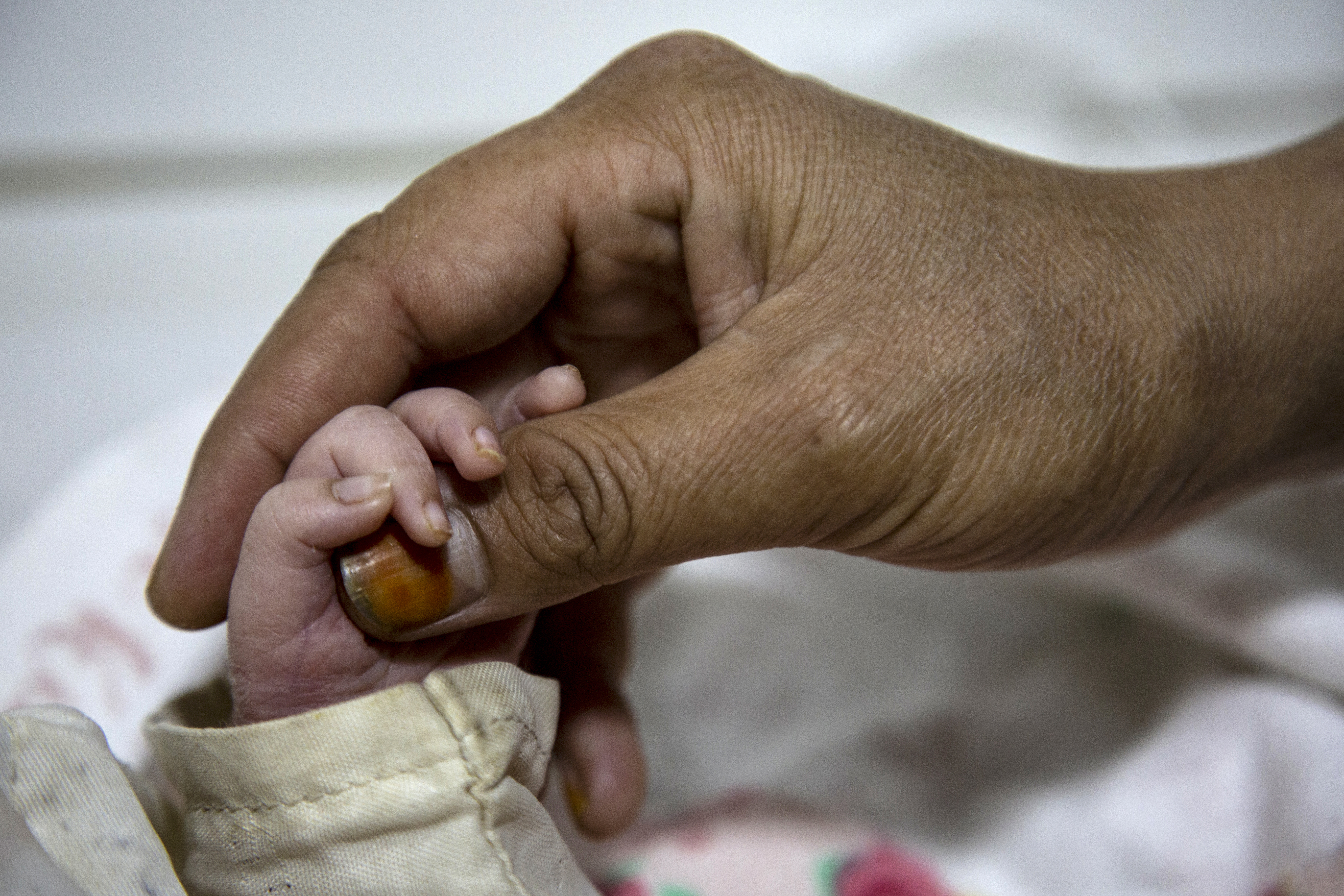 In this photograph taken on December 8, 2023, an Afghan woman holds the hand of her newborn child at the Doctors Without Borders (MSF)-run maternity hospital in Khost.
