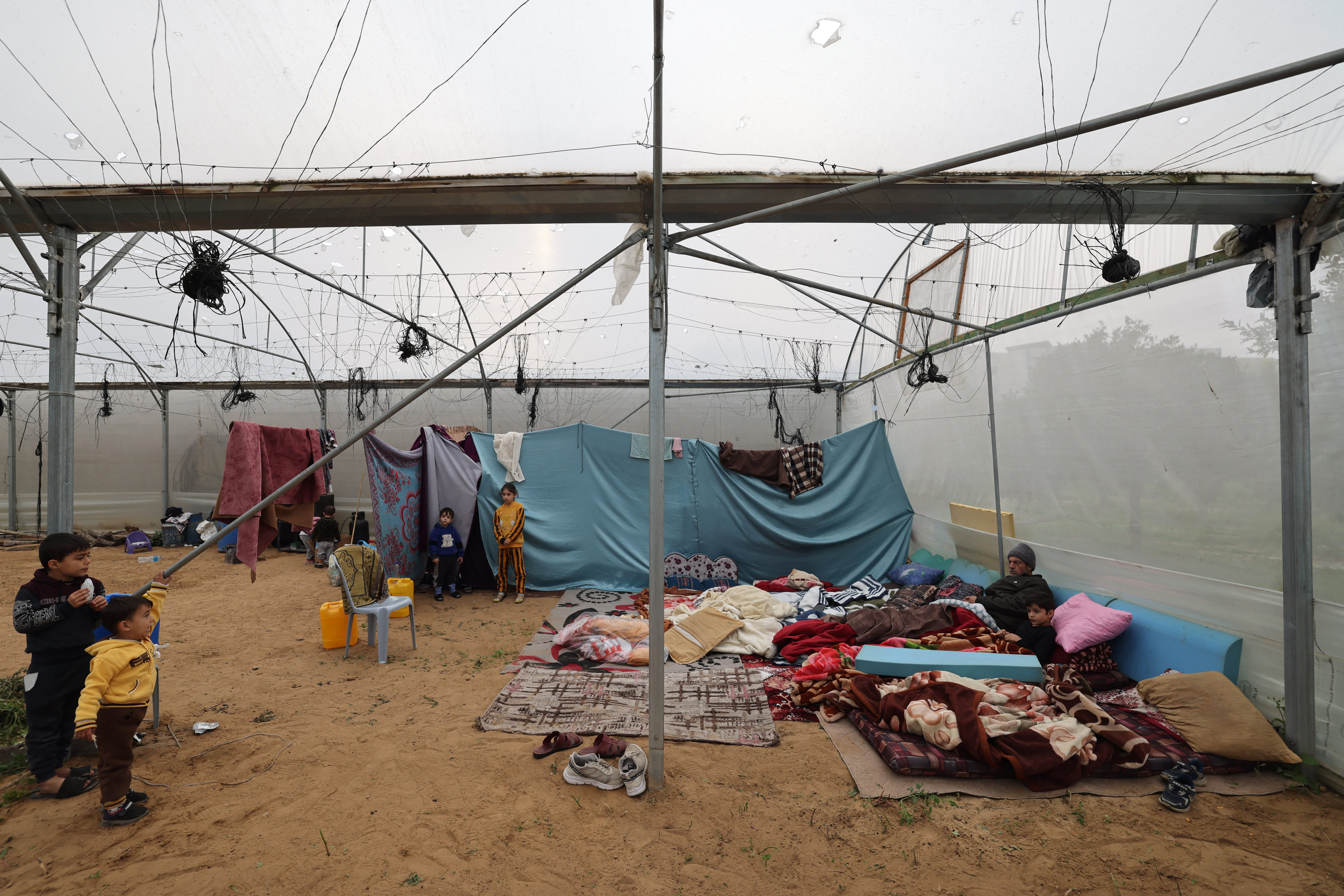 Palestinians, displaced by the Israeli bombardment of Khan Yunis, seek shelter inside an agricultural tent in Rafah in the southern Gaza Strip.