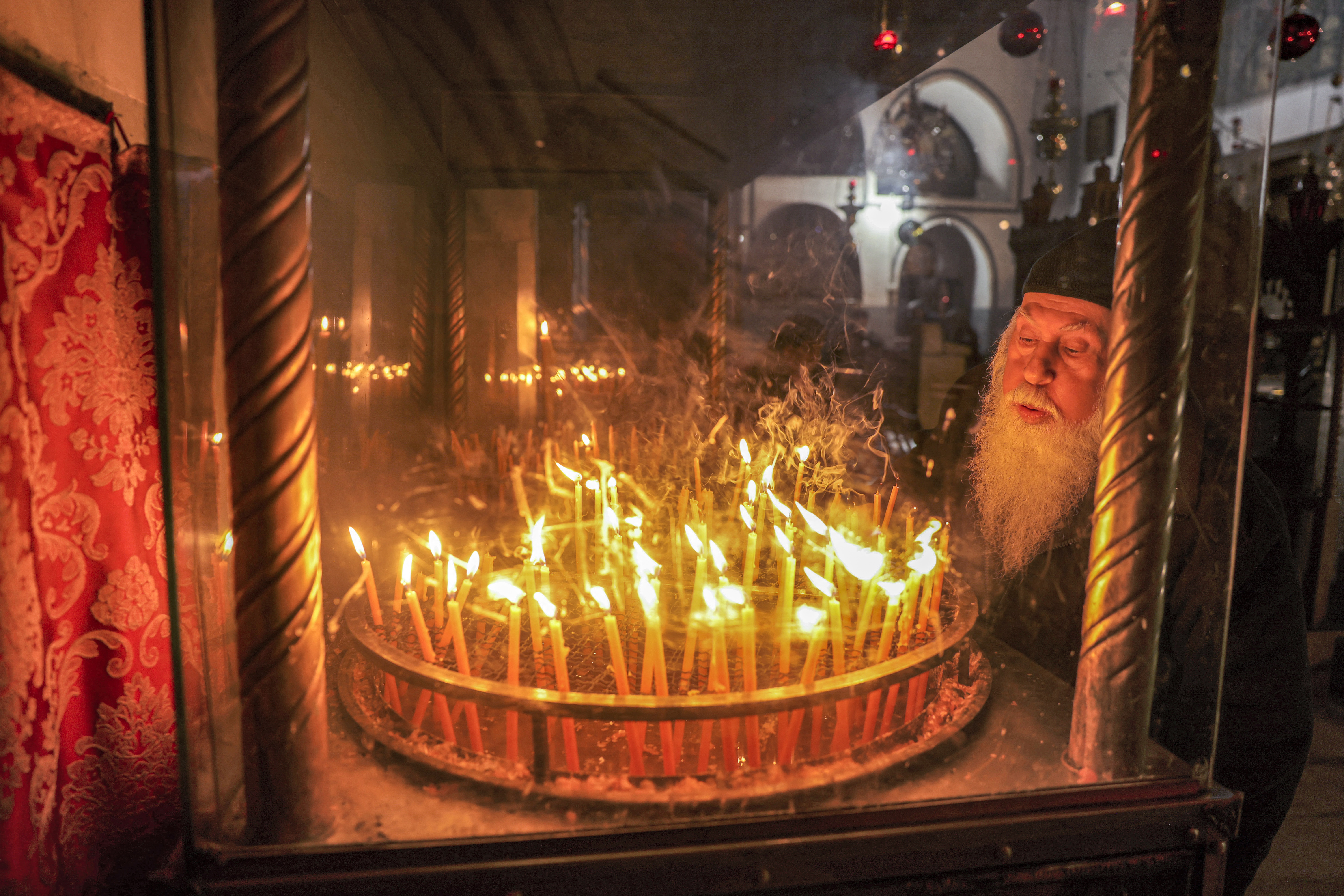 A Christian clergyman lights a candle before an icon at the Church of the Nativity in the biblical city of Bethlehem in the occupied West Bank