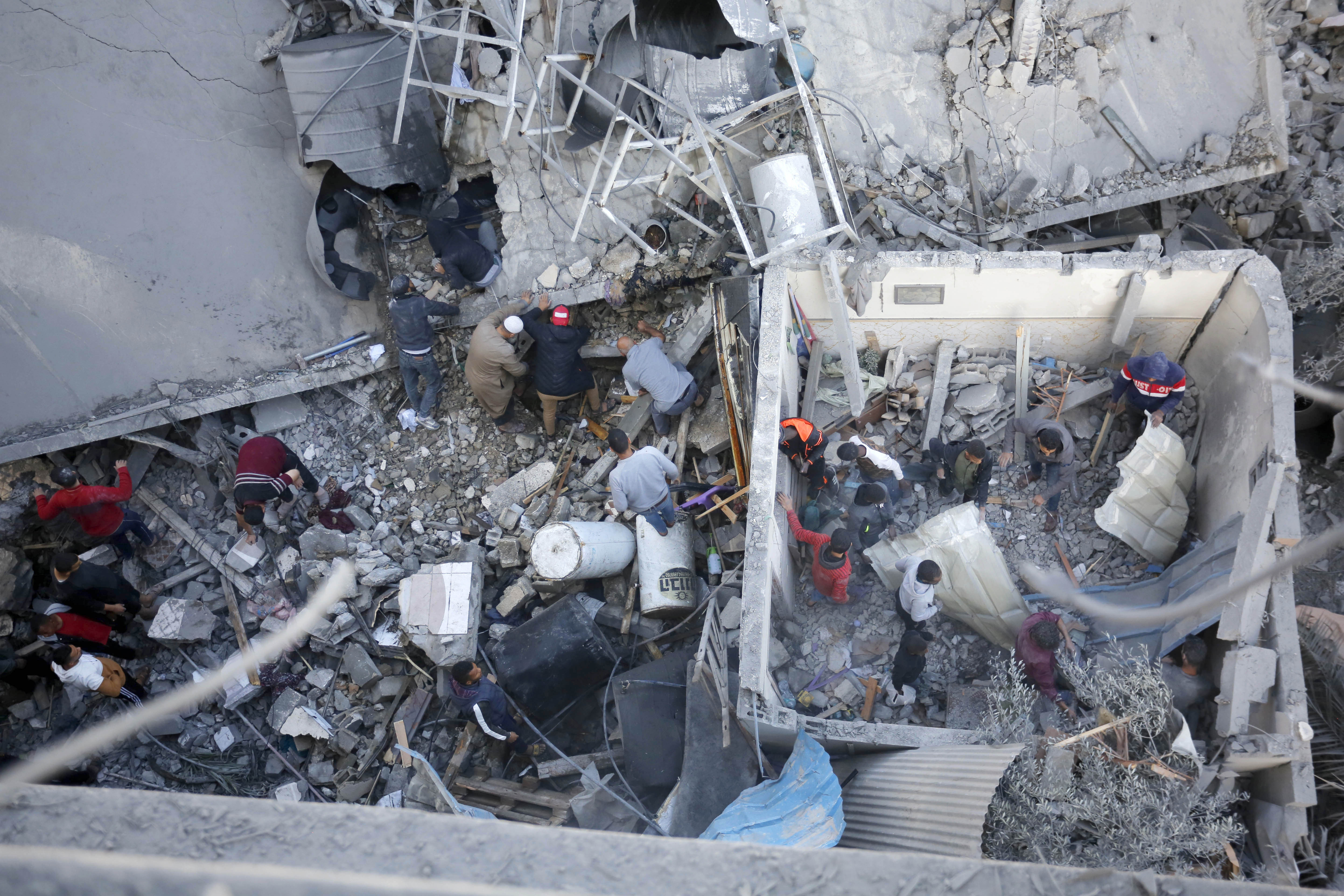 Residents and civil defense teams conduct a search and rescue operation among demolished buildings after Israeli attacks in Deir Al-Balah, Gaza.