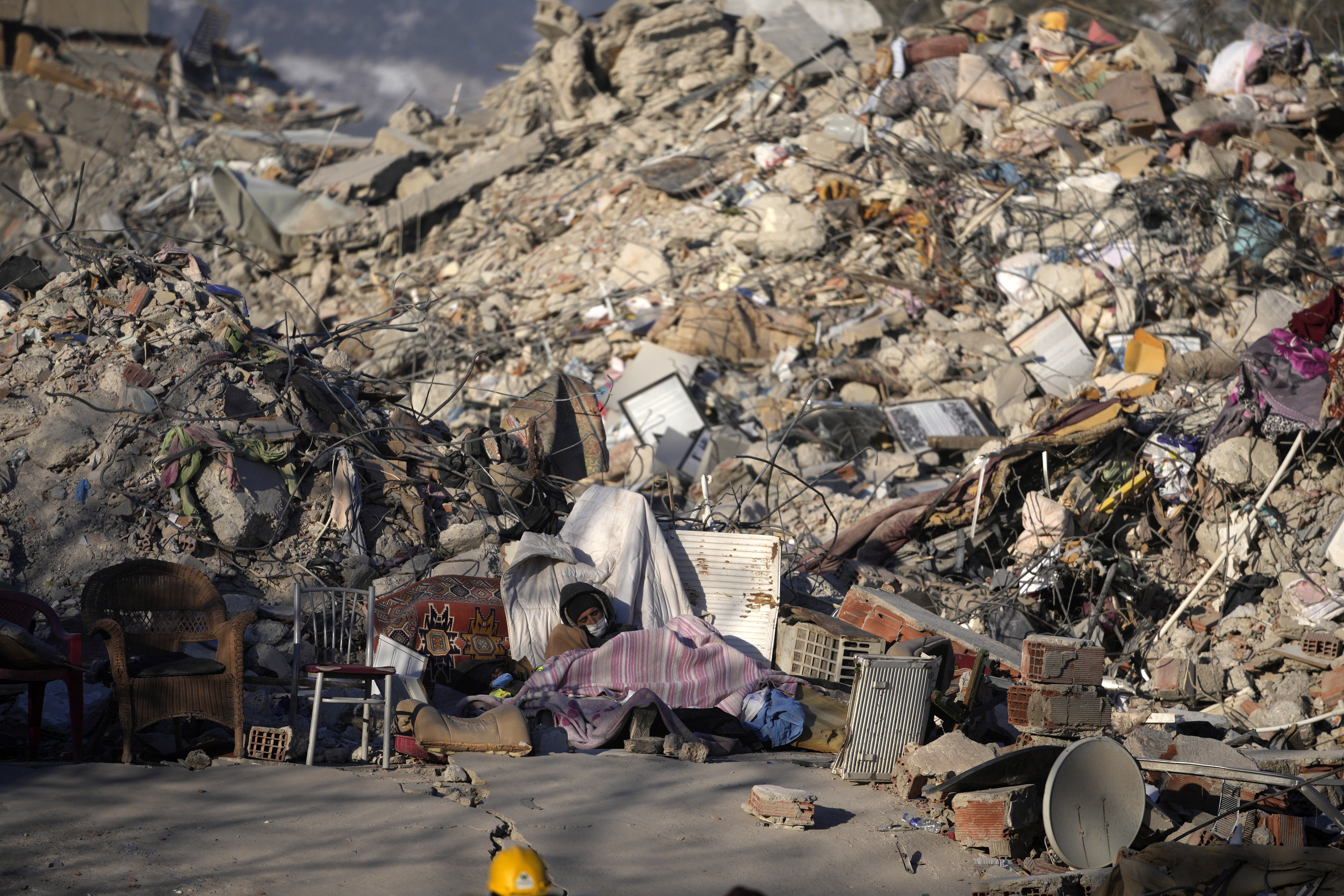A man sleeps in front of a destroyed building in Kahramanmaras, southeastern Turkey, Monday, Feb. 13